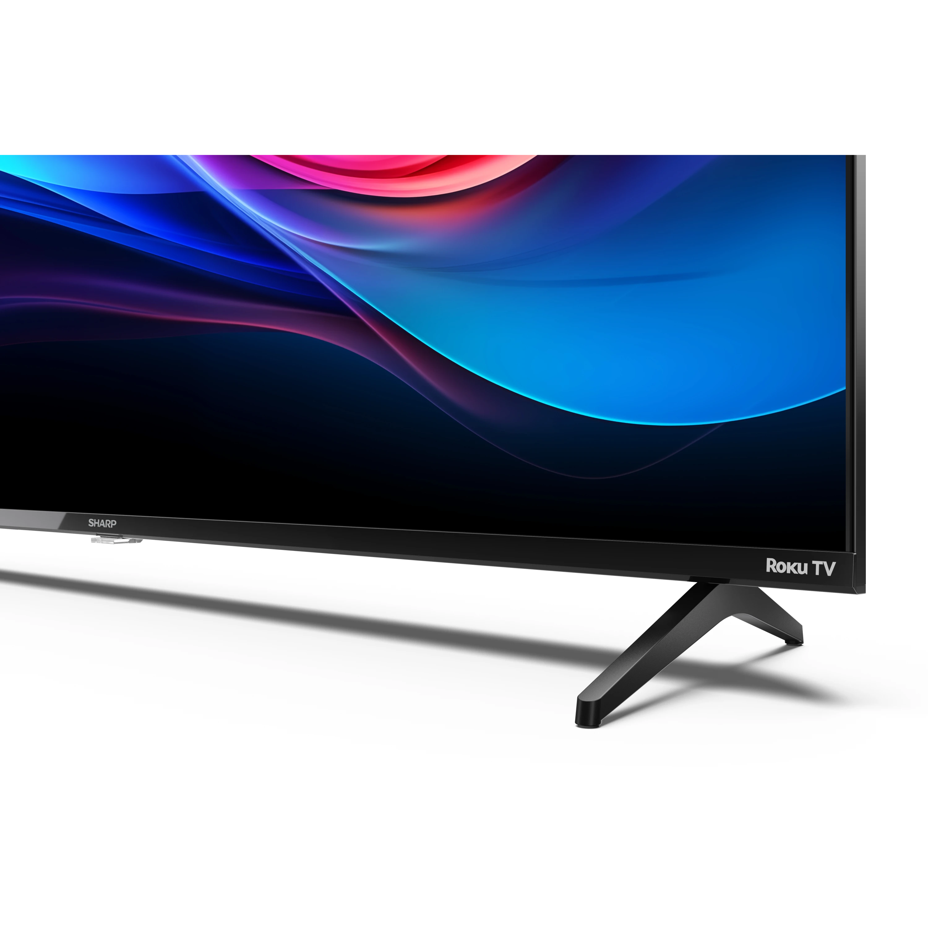 Nahaufnahme eines Sharp Roku TVs, der die untere Hälfte zeigt, mit einem schwarzen Ständer auf weißem Untergrund.