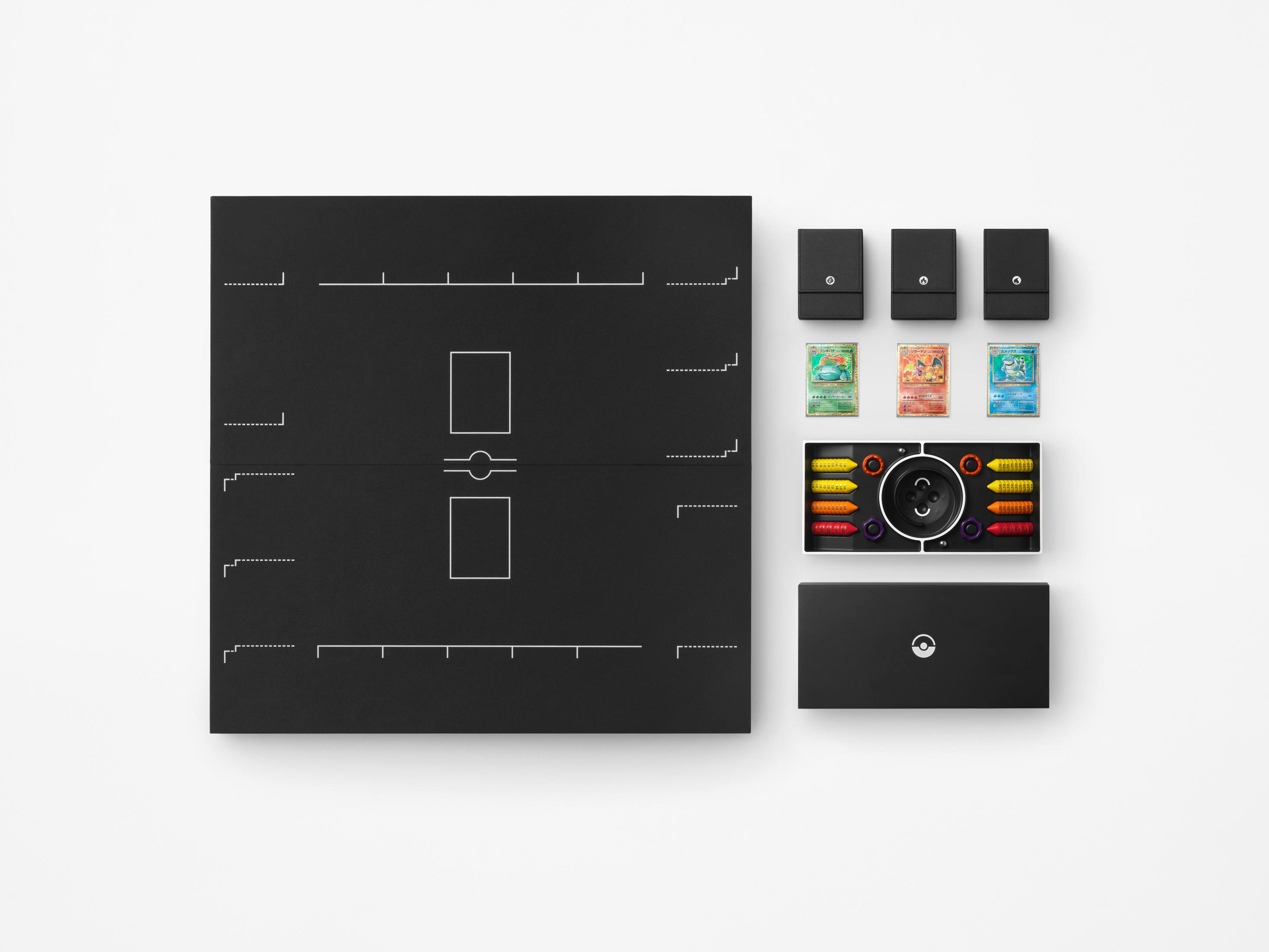 Tapis de jeu noir avec cartes, pochettes et une manette sur une surface blanche.