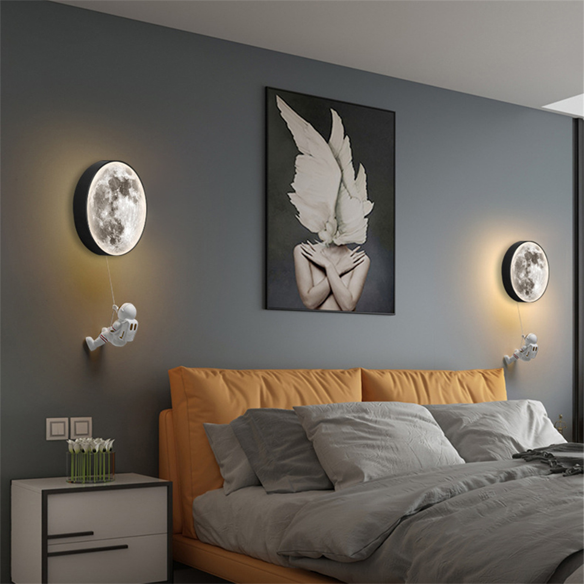 Schlafzimmer mit zwei mondförmigen Lampen und jeweils einem Astronauten. Es gibt ein abstraktes Kunstwerk.