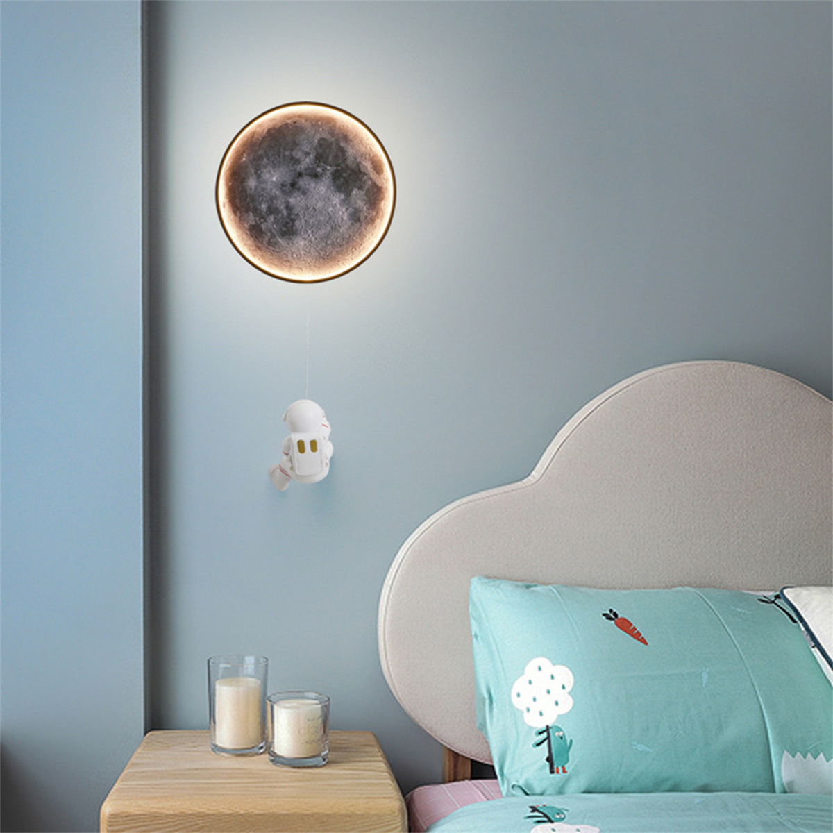 Eine mondförmige Lampe mit Astronautendekoration, die in der Nähe eines Bettes hängt. Blaue Wand.