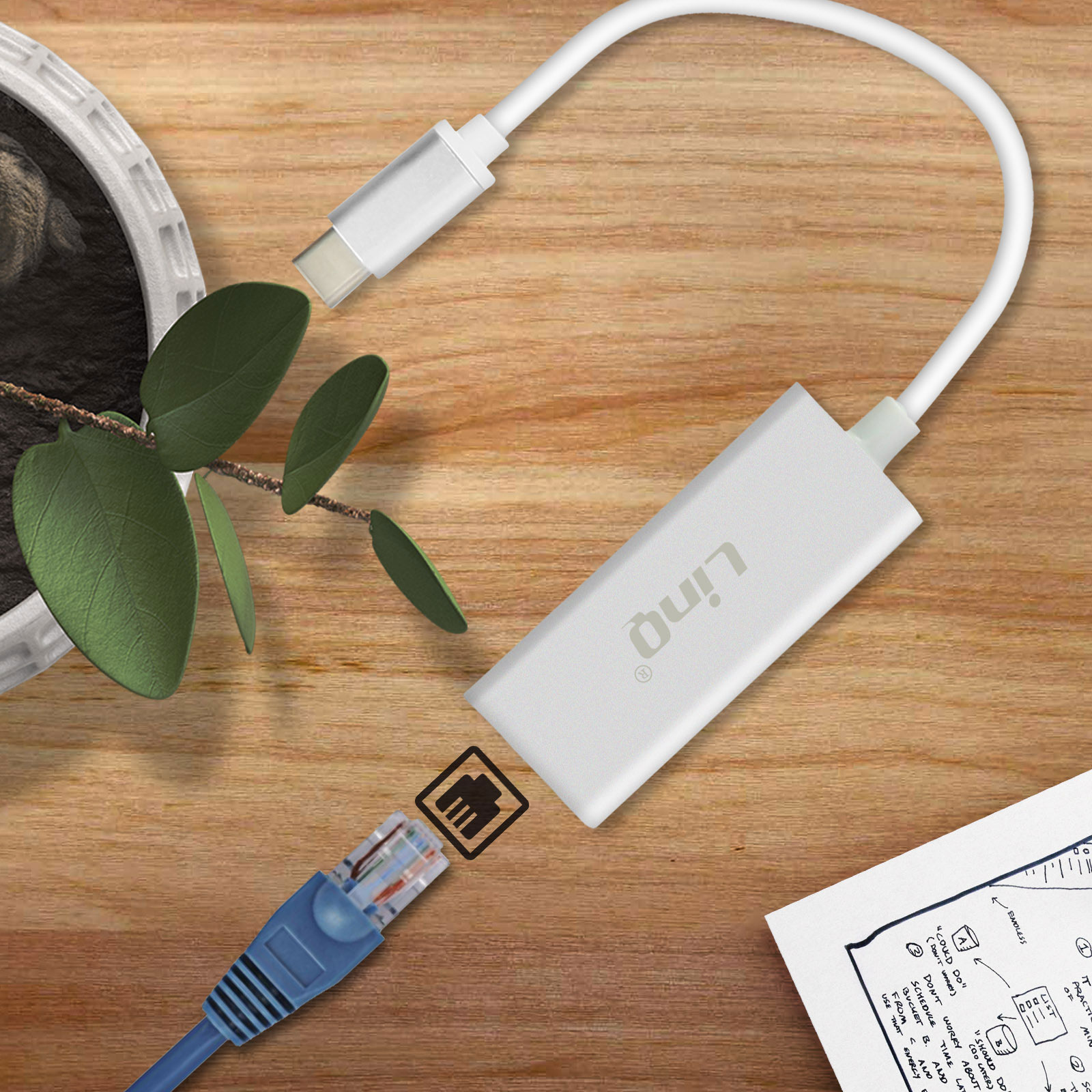 Adattatore da USB-C a Ethernet bianco collegato a un cavo Ethernet blu, su una superficie di legno.
