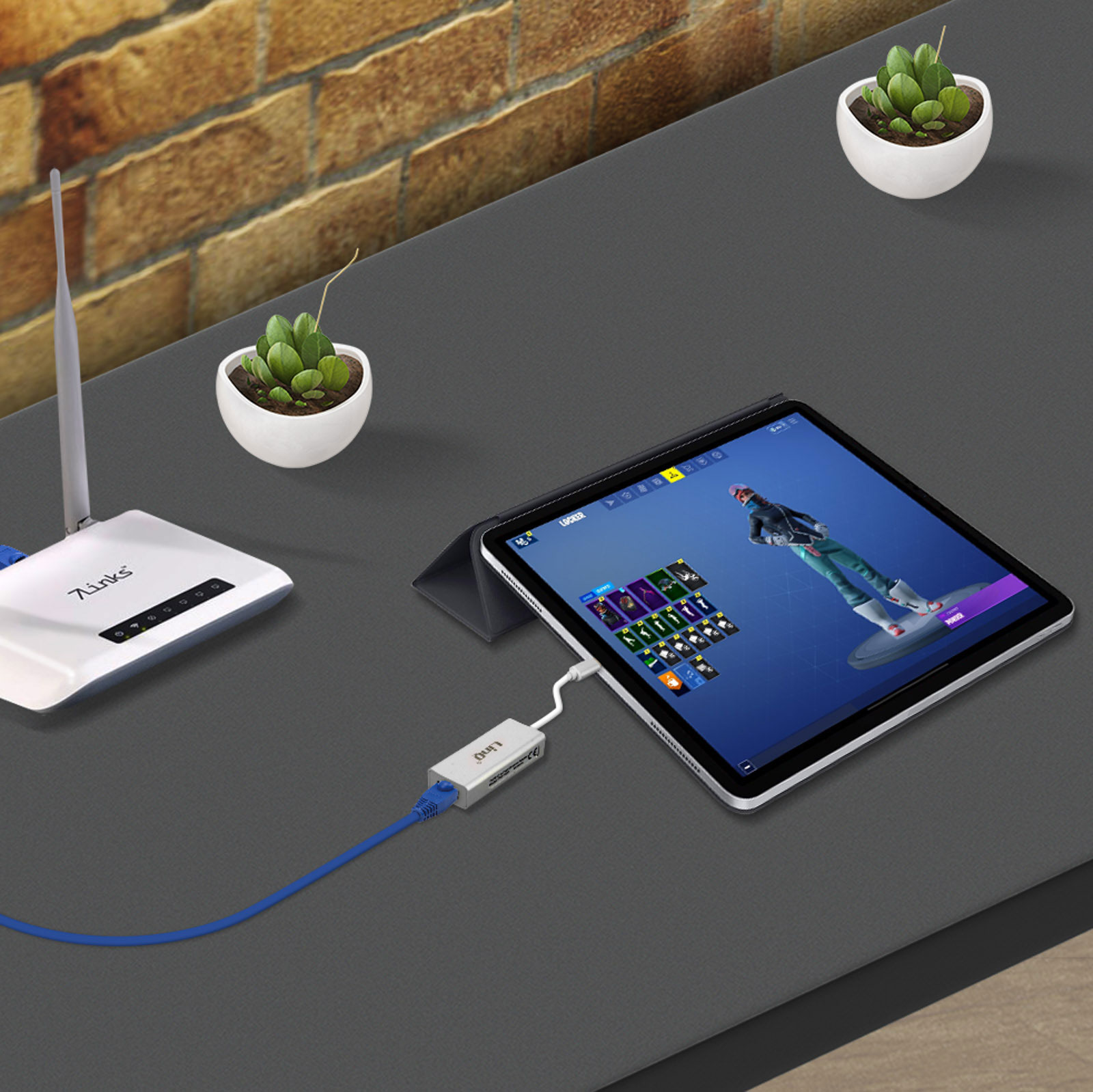 Tablet collegato a un router e due piccole piante.