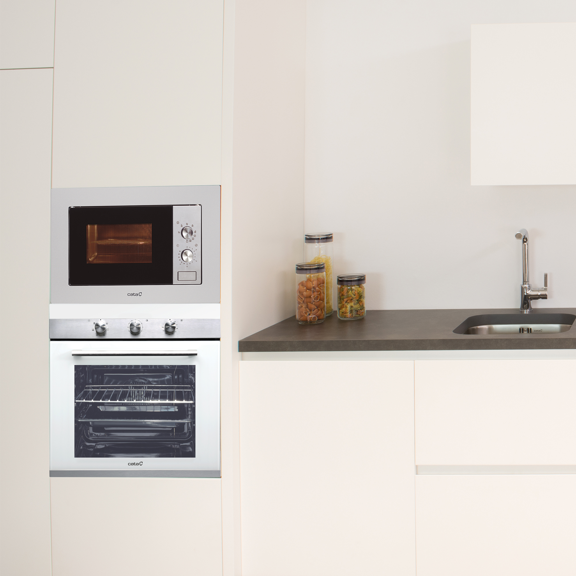 Cocina con microondas sobre horno y tarros de comida en la encimera.