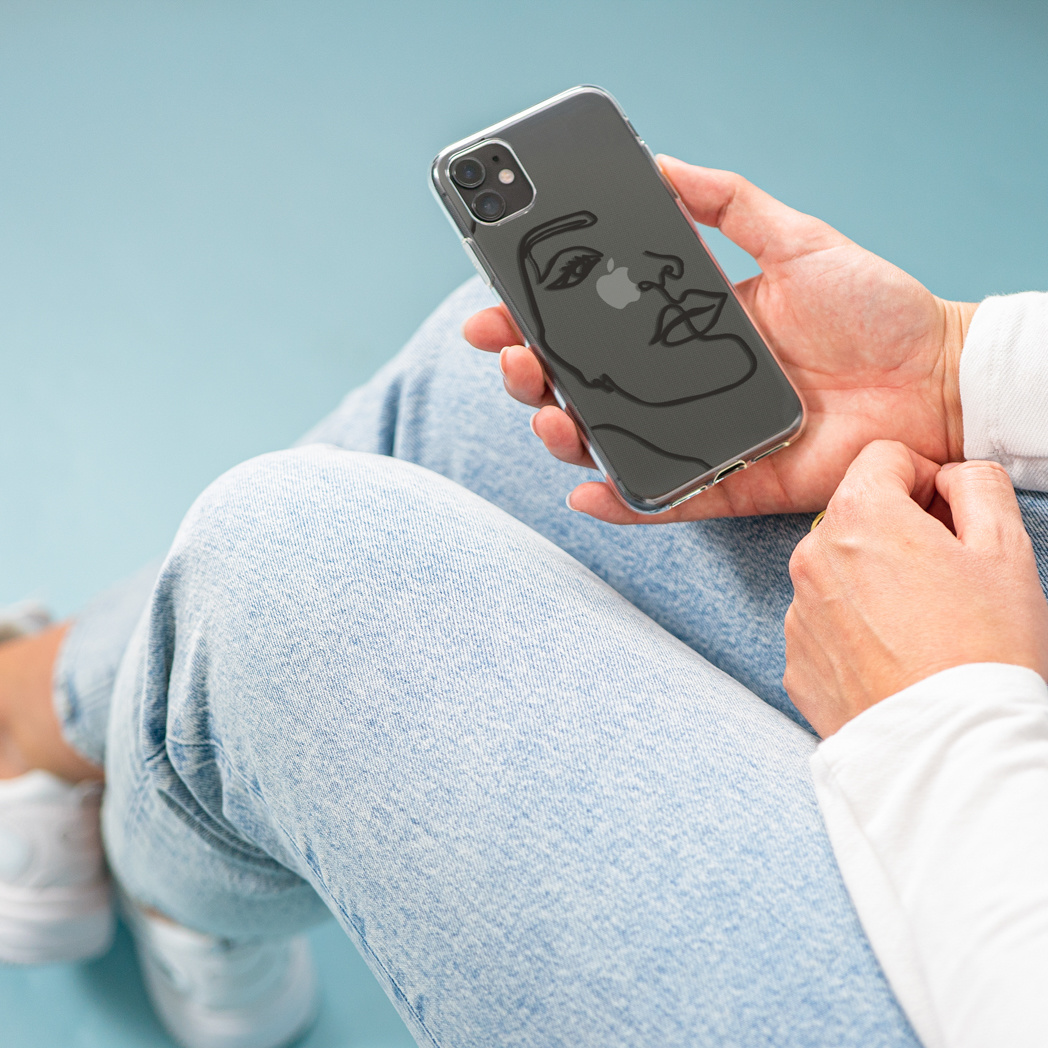 Persoon houdt een telefoon vast in een hoesje met een zwarte lijntekening van een gezicht.