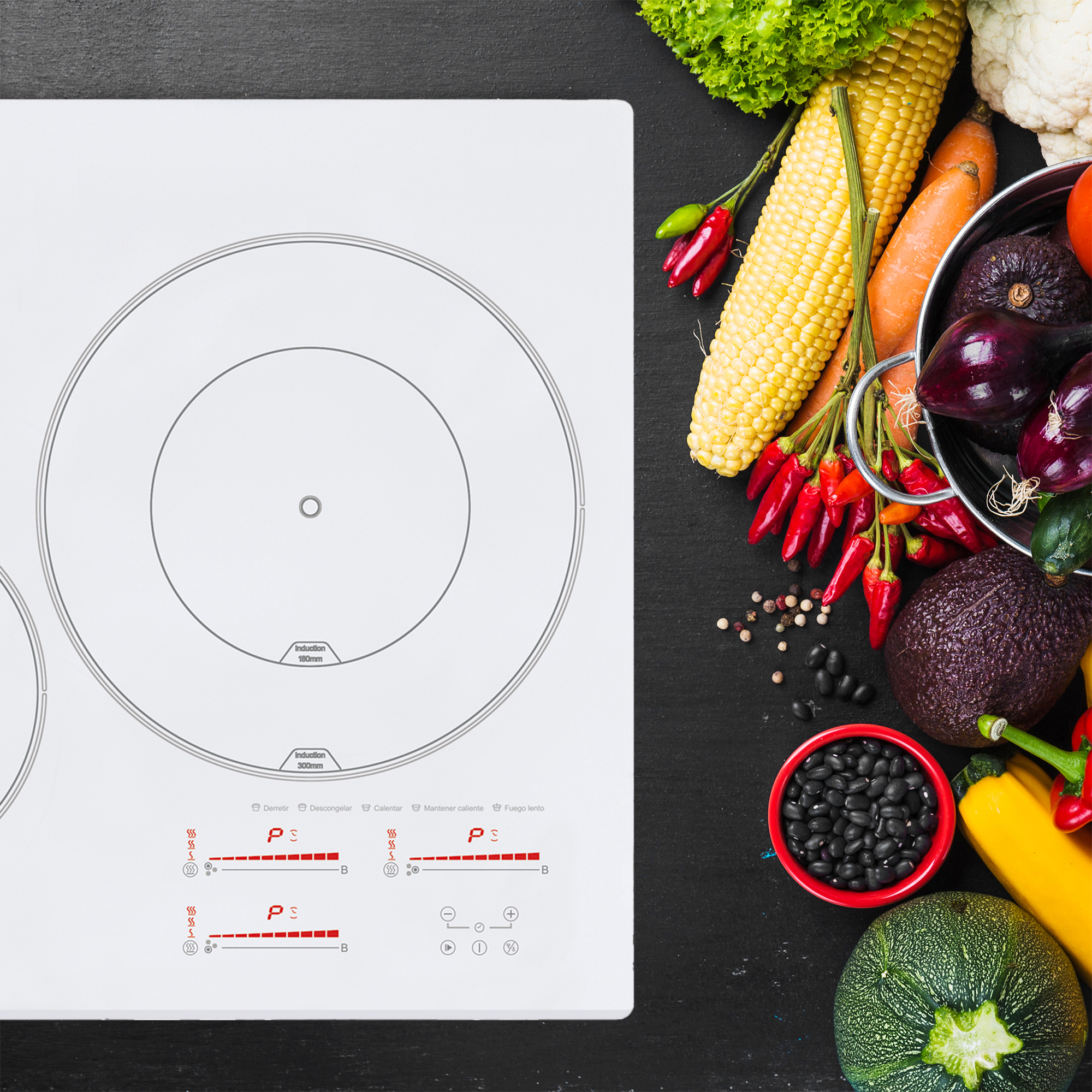 Biała płyta indukcyjna z dwoma palnikami i różnymi warzywami na czarnej powierzchni.