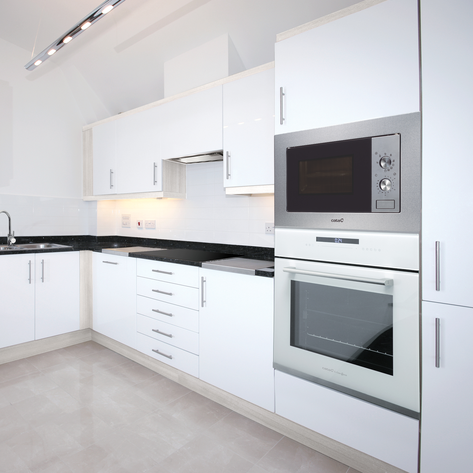 Una cocina blanca moderna con gabinetes blancos, un microondas y un horno de acero inoxidable. Encimera negra.