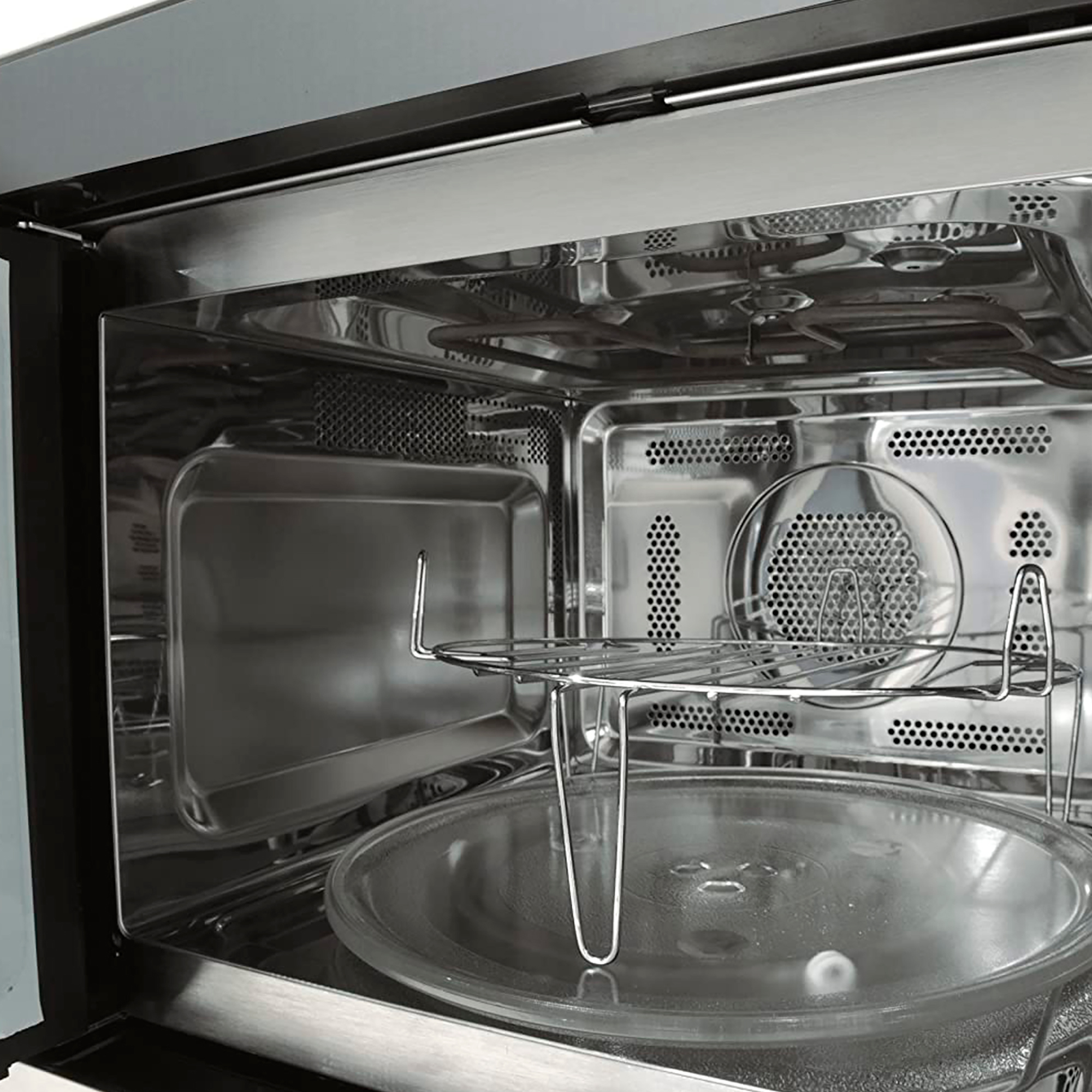 Wnętrze kuchenki mikrofalowej. Pokazuje szklany talerz, metalowy stojak i szczegóły wnętrza.