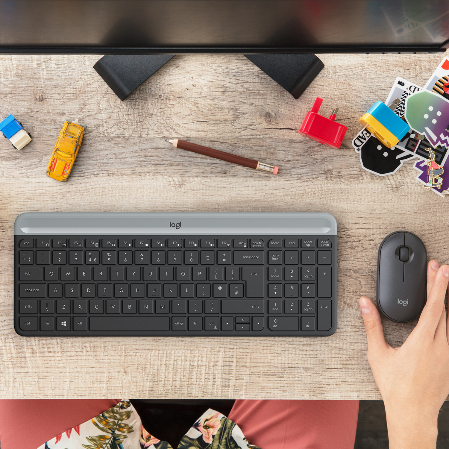 Tastatur und Maus auf einem Holztisch mit Spielzeug und anderen Gegenständen.