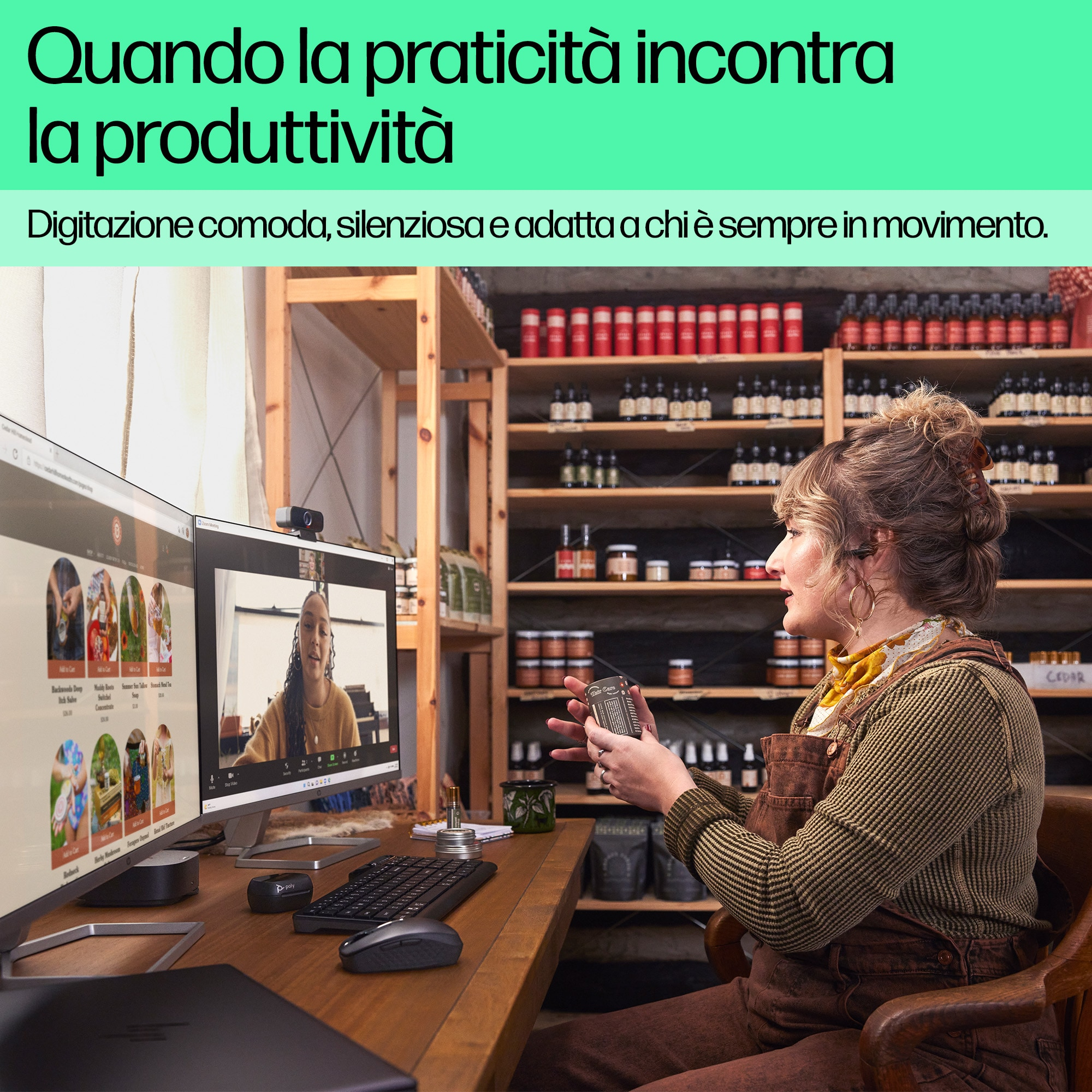 Una mujer usando una computadora con dos pantallas. Un estante con objetos en el fondo.