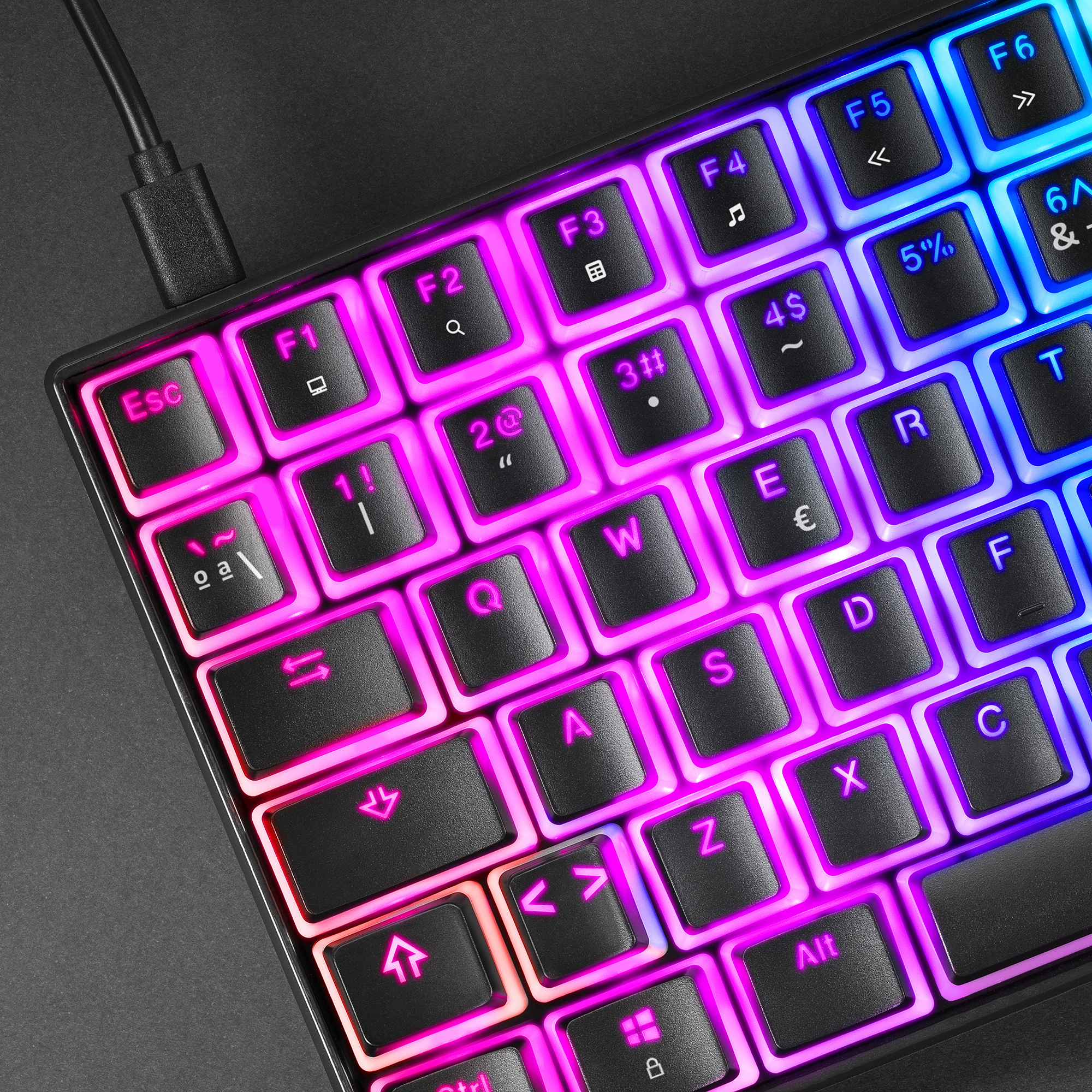 Nahaufnahme einer kleinen, farbenfrohen Tastatur mit beleuchteten Tasten und einem schwarzen Kabel.