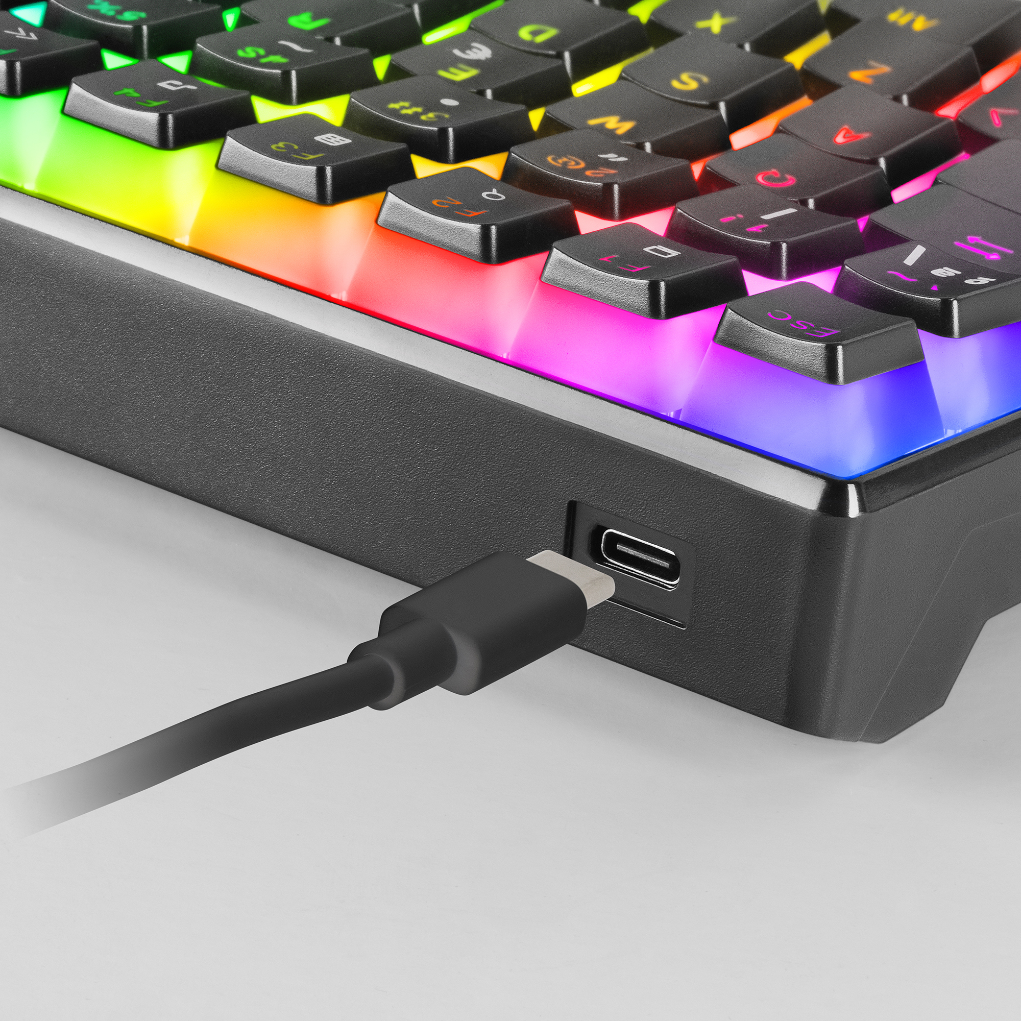Nahaufnahme einer Tastatur mit Regenbogenbeleuchtung unter den Tasten. Ein USB-C-Kabel ist eingesteckt.