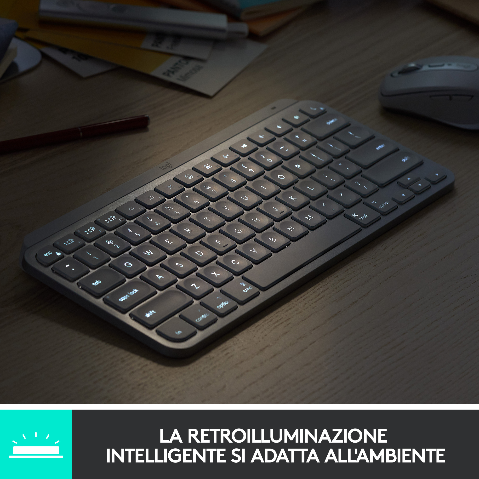 Tastiera grigia illuminata su scrivania in legno, con mouse sullo sfondo.
