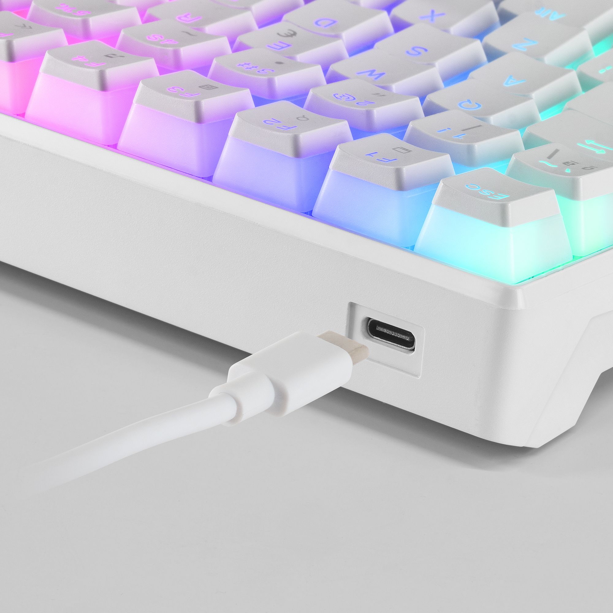 Nahaufnahme einer weißen Tastatur mit bunten Tastenlichtern. Ein weißes Ladekabel ist eingesteckt.
