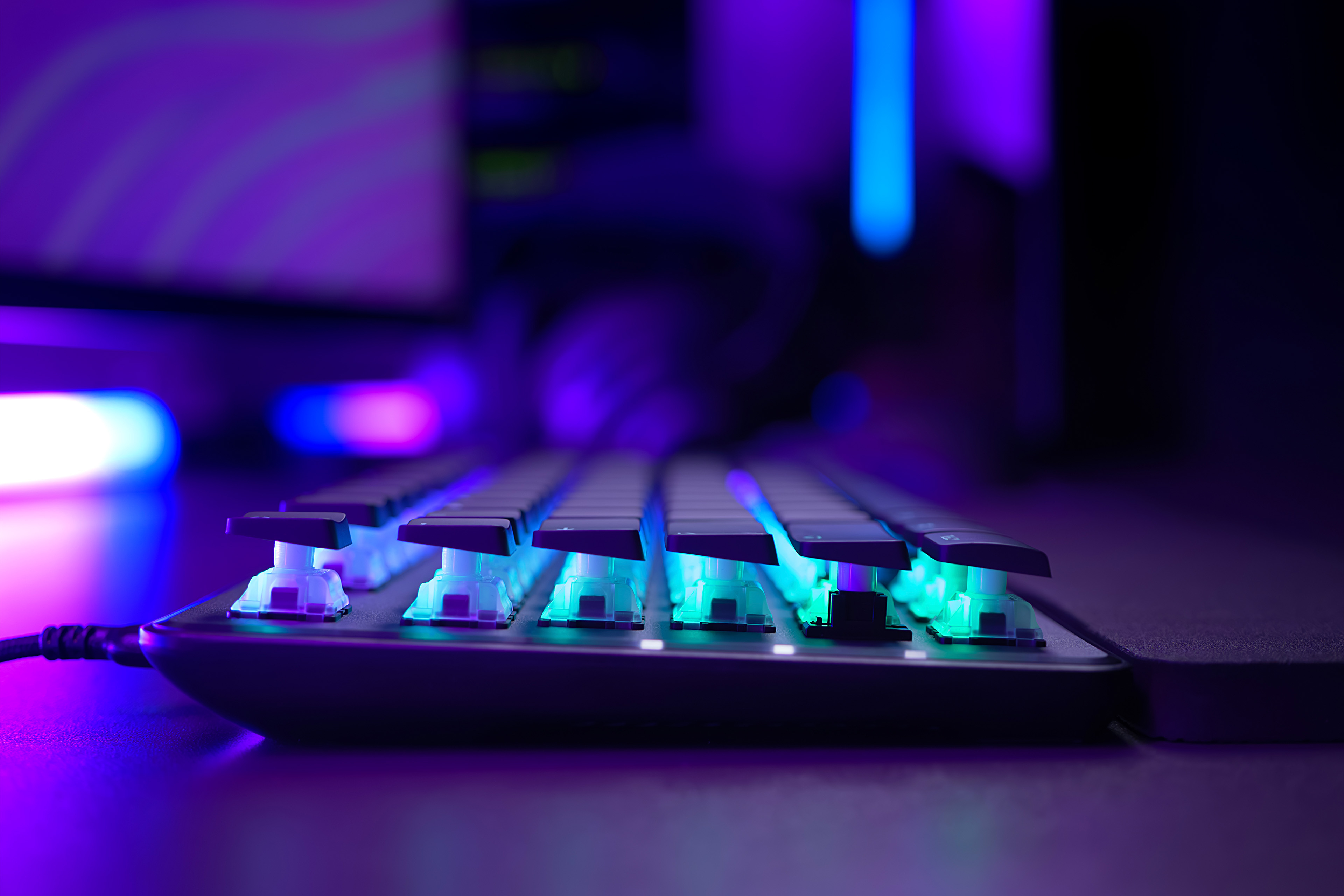 Seitenansicht einer hintergrundbeleuchteten Tastatur mit blauen und grünen Lichtern.