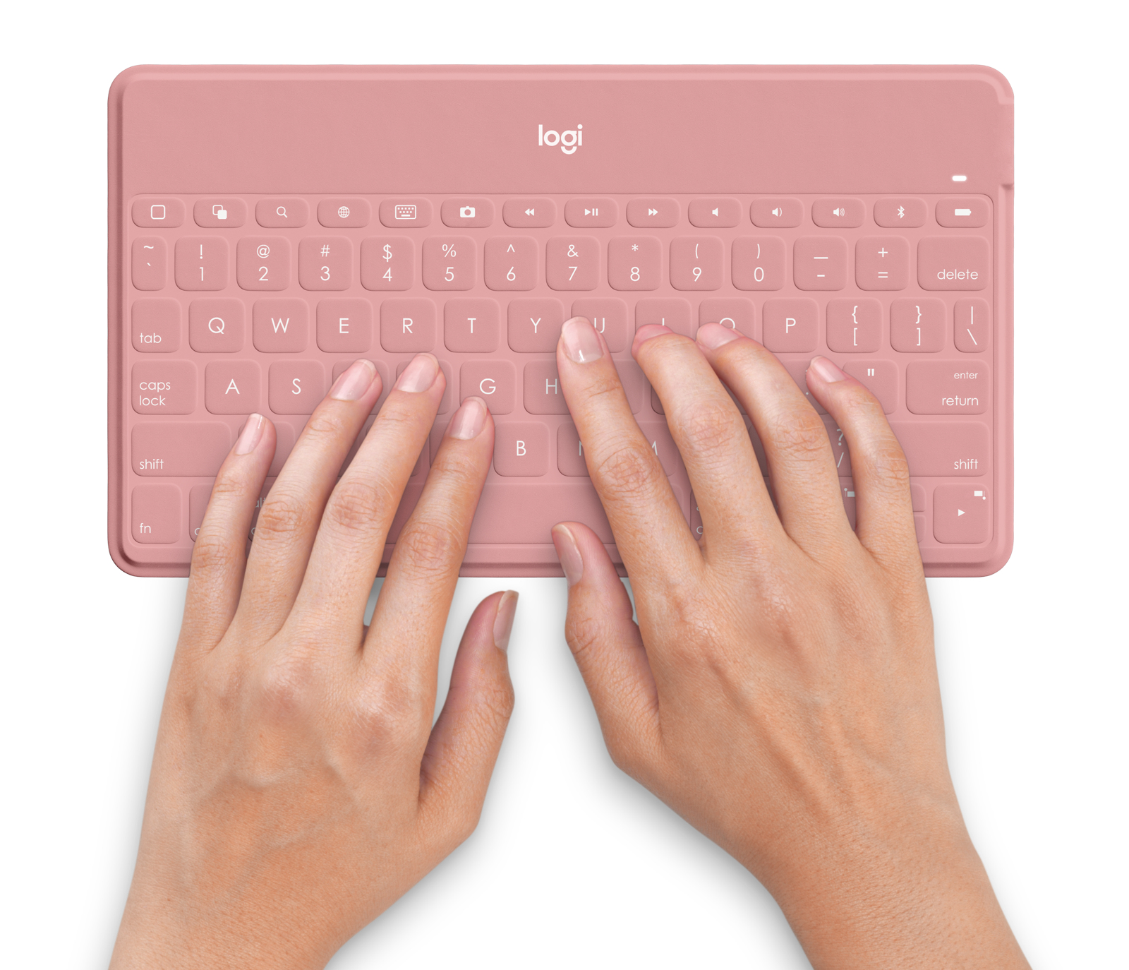 Manos escribiendo en un teclado Logitech rosa, fondo blanco, toma cenital.