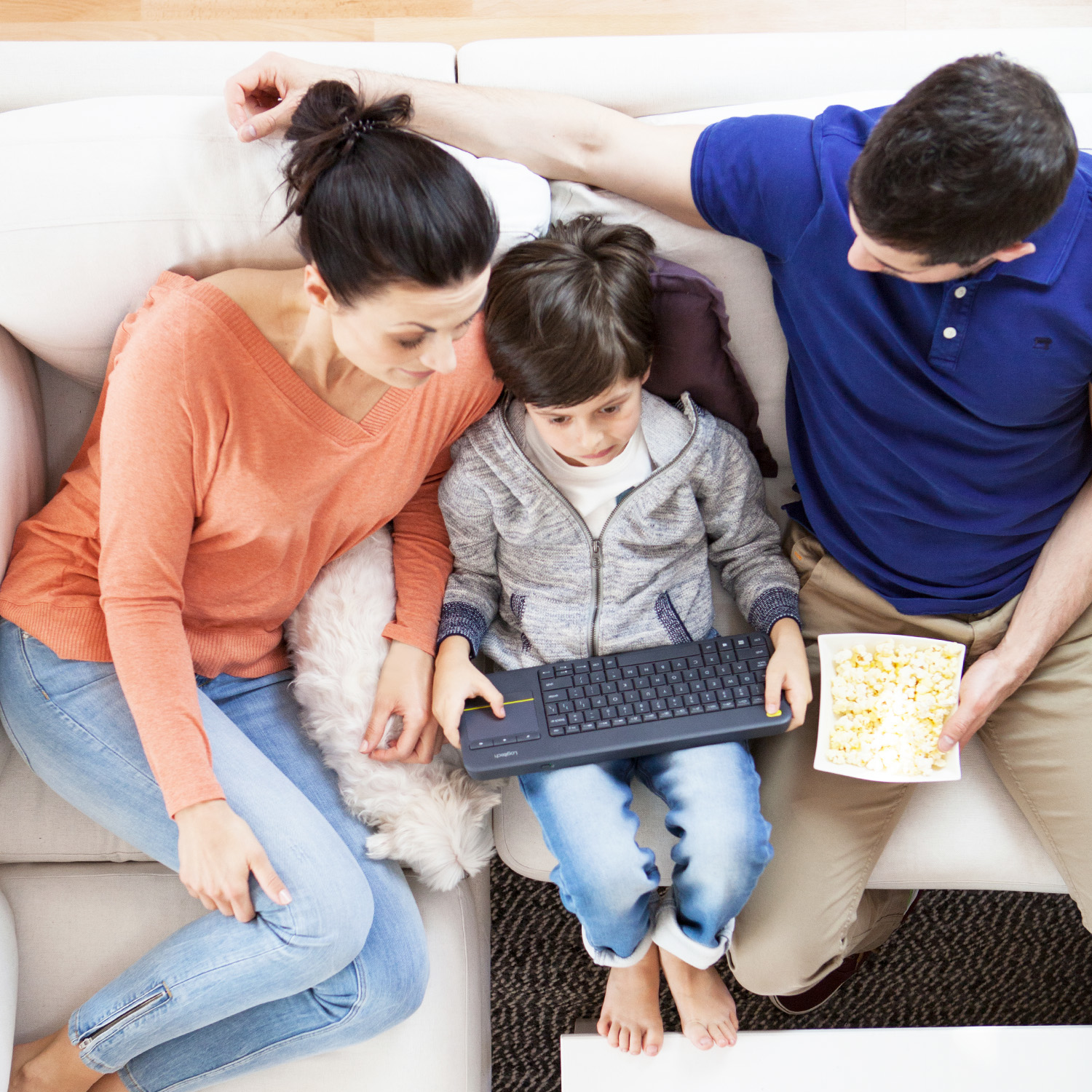 Rodzina na kanapie z klawiaturą i popcornem, ujęcie z góry.