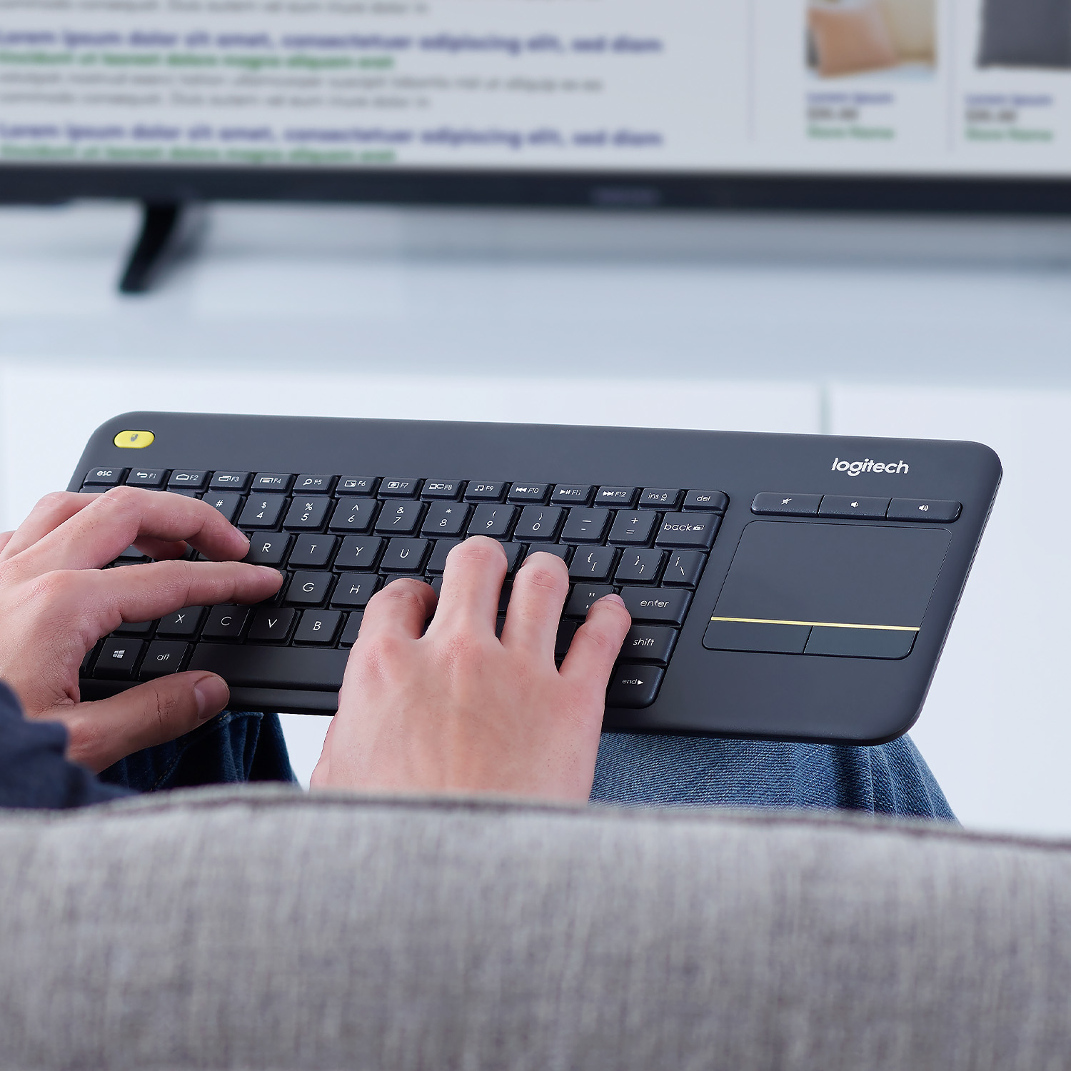 Osoba używająca czarnej klawiatury z gładzikiem. Telewizor w tle.