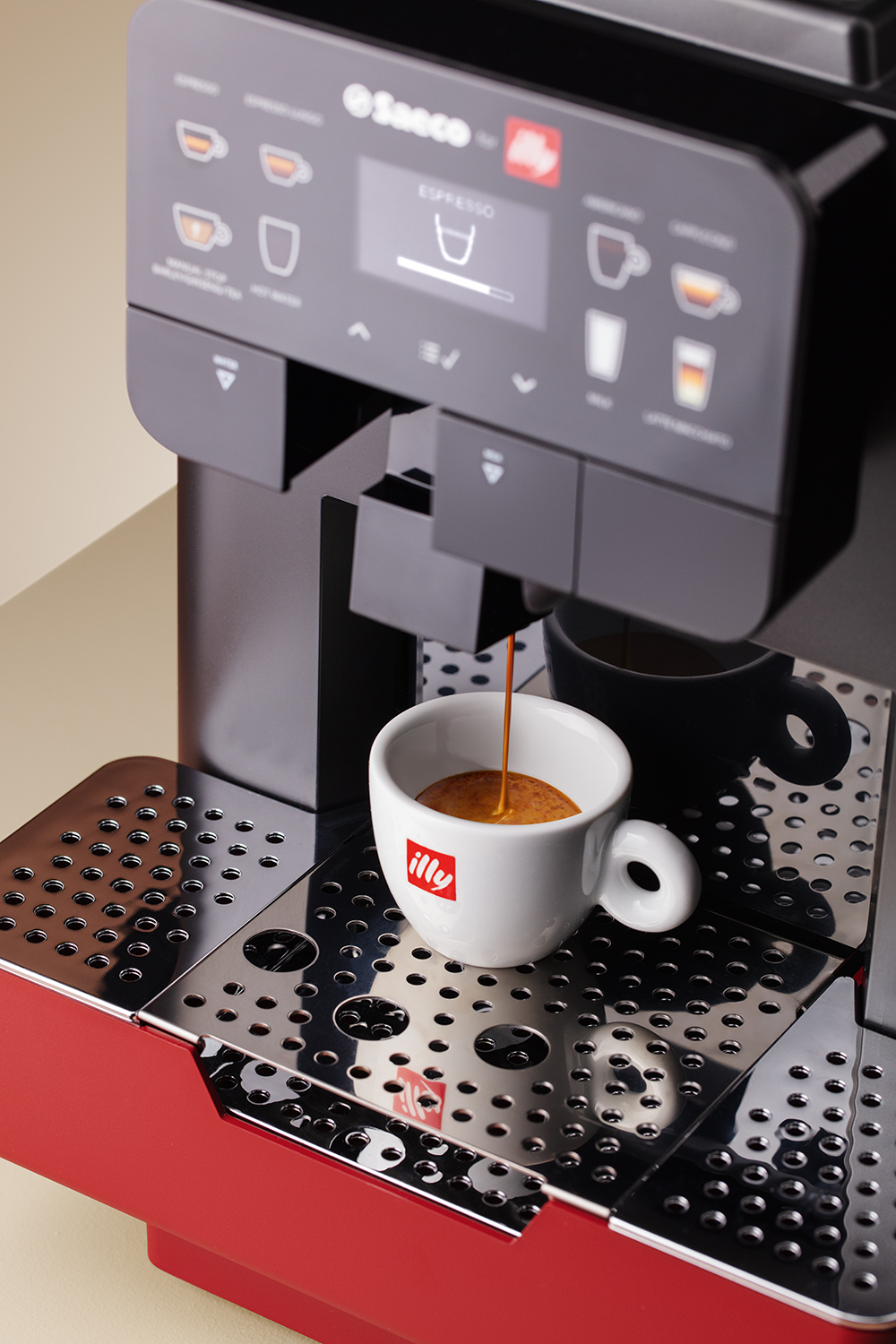 Máquina de espresso con taza blanca llenándose. Base roja, parte superior negra.