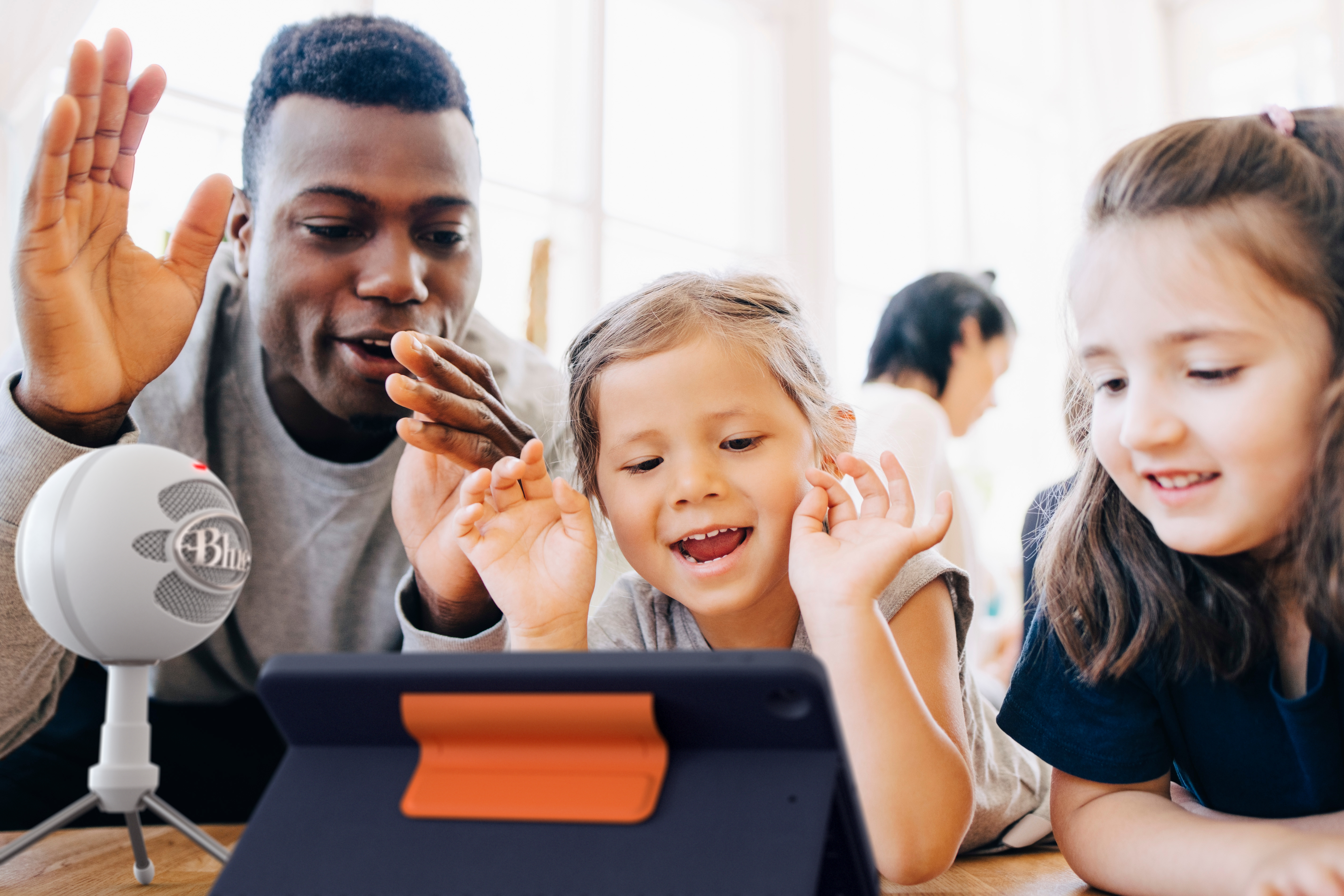 Uomo e bambini guardano un tablet, microfono vicino.
