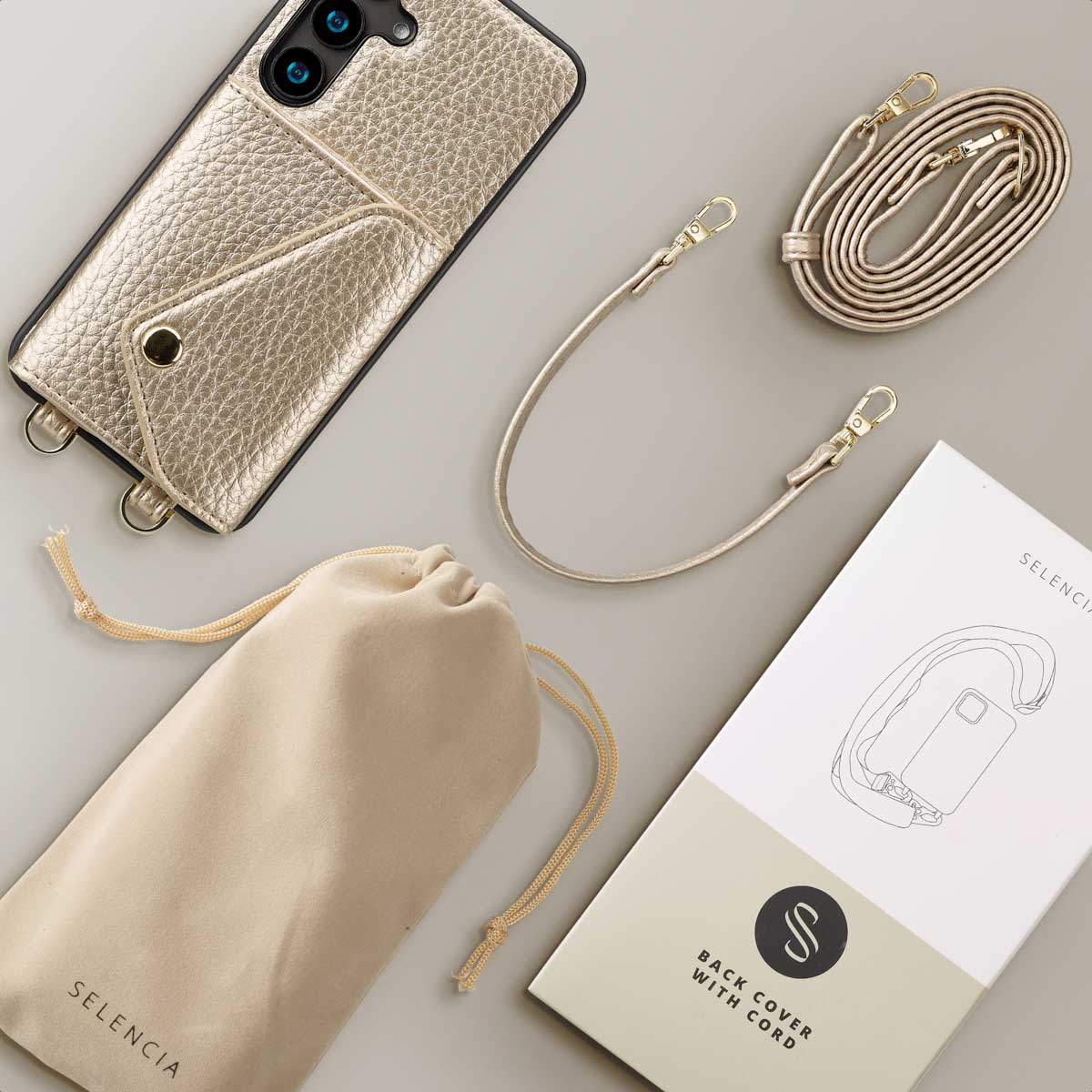 Een telefoonhoesje met een riem, een tas en verpakking op een wit oppervlak.