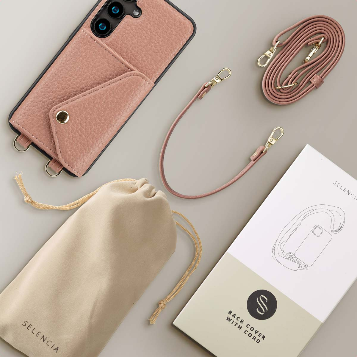 Een roze telefoonhoesje met riem, zakje en doos.