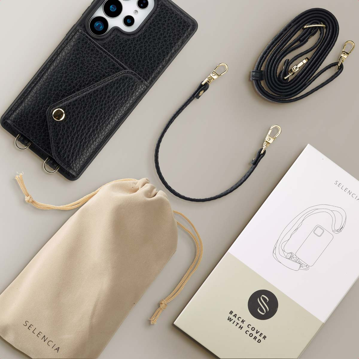 Zwart telefoonhoesje met bandje, etui en accessoires. Beige achtergrond.