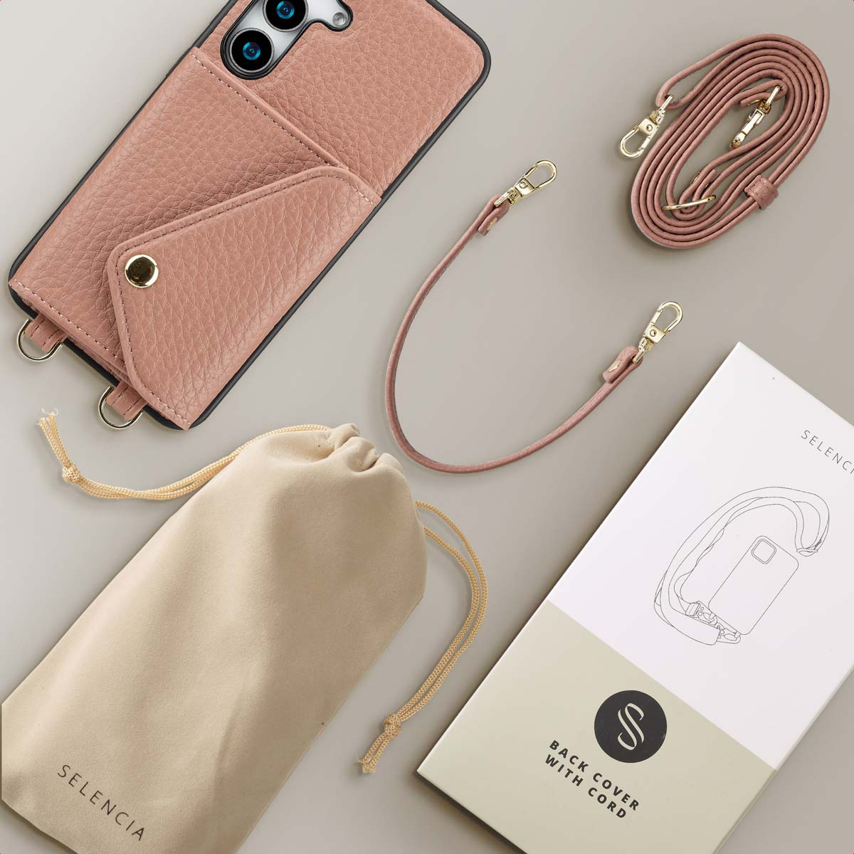 Roze telefoonhoes met een riem en een klein vakje voor kaarten. Accessoires waaronder een doos.