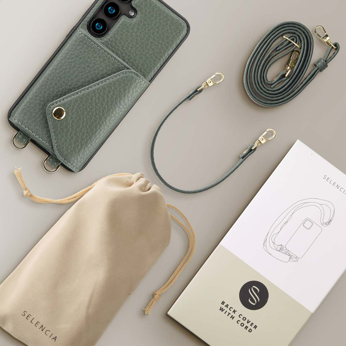 Groene telefoonhoes met riem, tas en doos. Artikelen liggen op een lichtgrijze ondergrond.