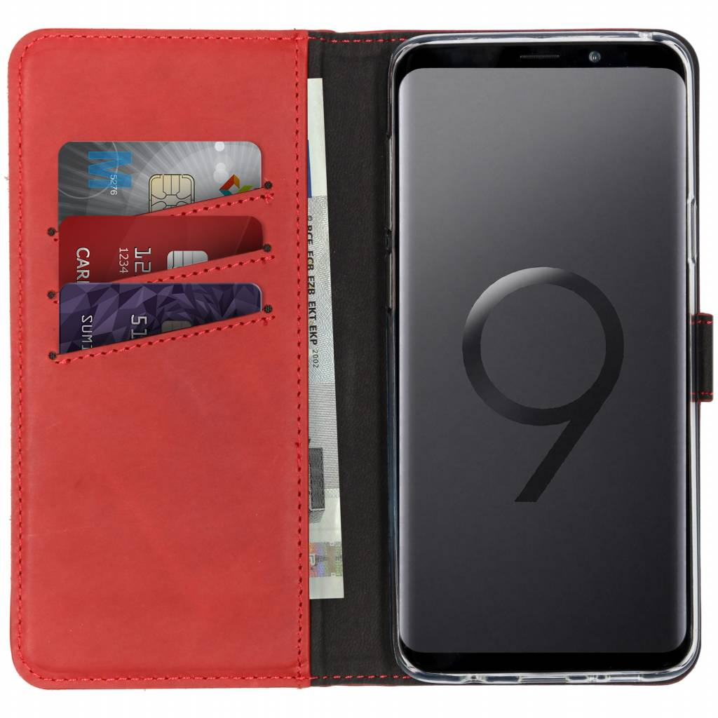 Étui portefeuille rouge ouvert. Cartes et argent visibles. Téléphone à droite.