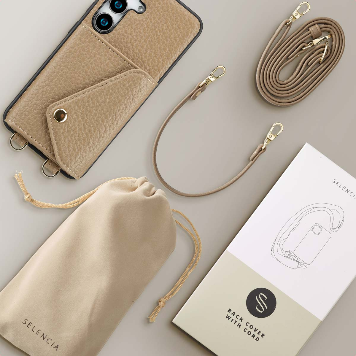 Tan telefoonhoesje met band en accessoires, waaronder een zakje en een doos.