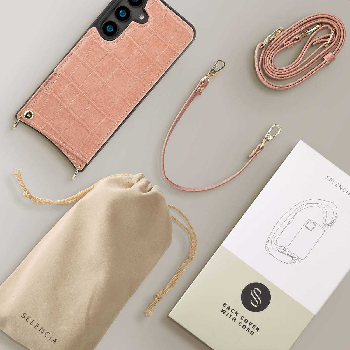 Roze telefoonhoesje met riem, tas en doos. Roze telefoonhoesje, riem en tas. Doos toont een afbeelding.