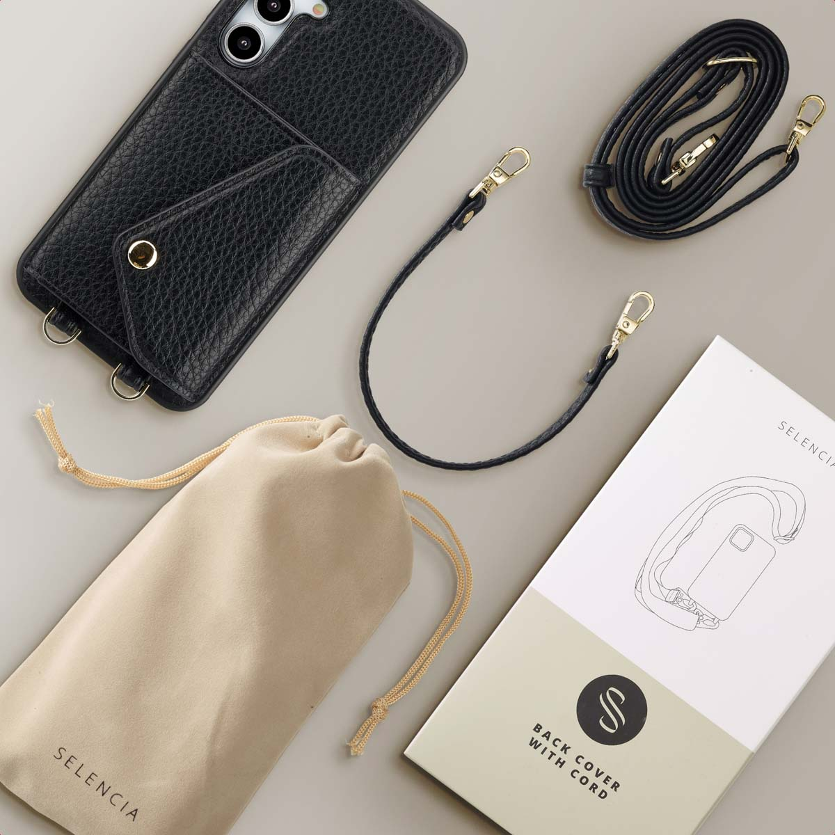 Zwarte telefoonhoes met band en accessoires, waaronder een zakje en een doos.