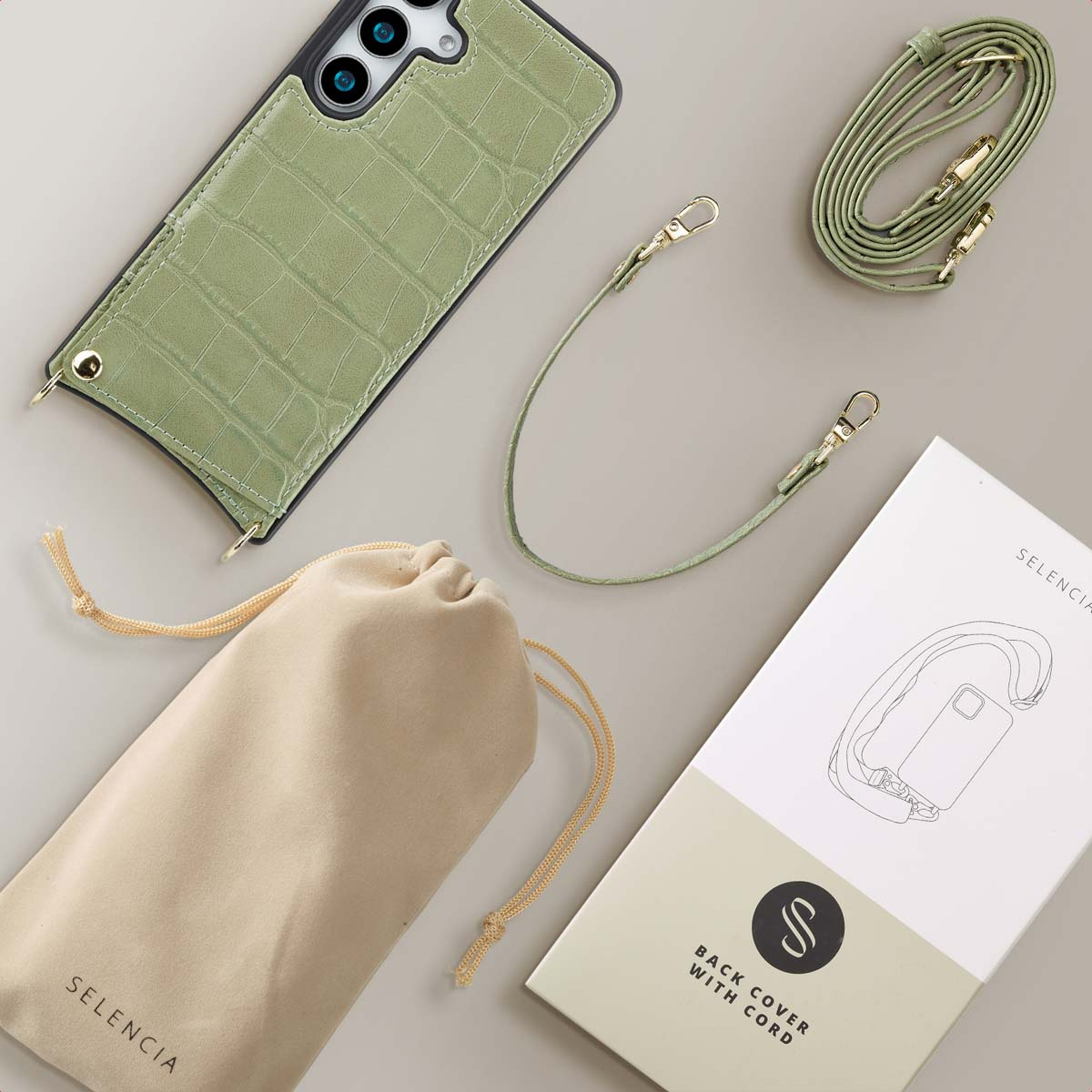 Groene telefoonhoes met riem, beige zakje en doos.