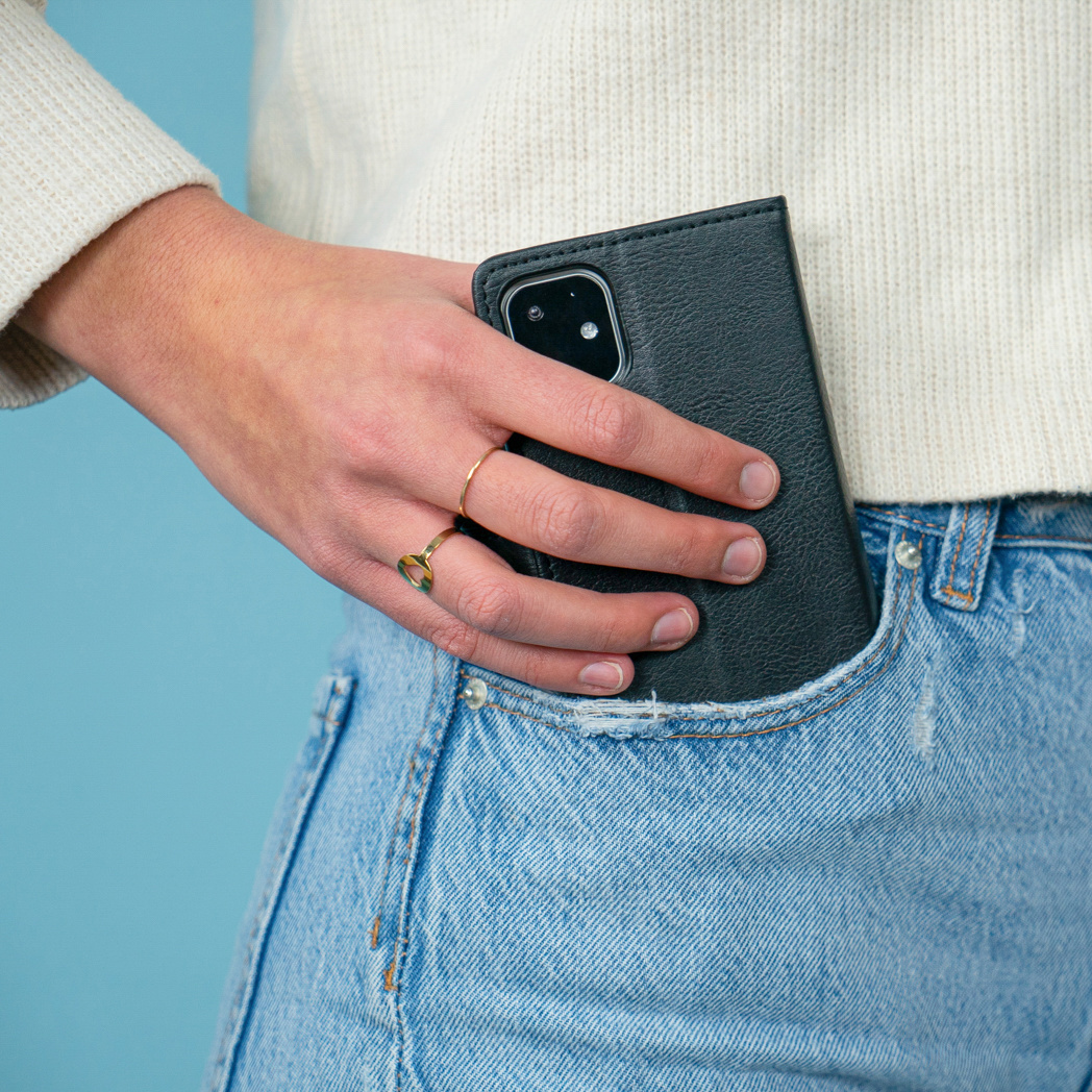 Mano in tasca dei jeans che tiene una custodia nera per telefono.