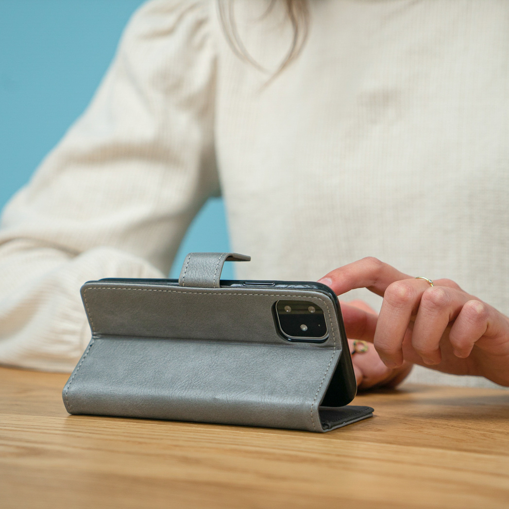 Telefoonhoes openstaand op een tafel. Een persoon raakt het telefoonscherm aan.