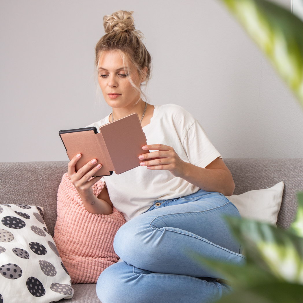 Femme lisant un livre sur un canapé, chignon, jean.