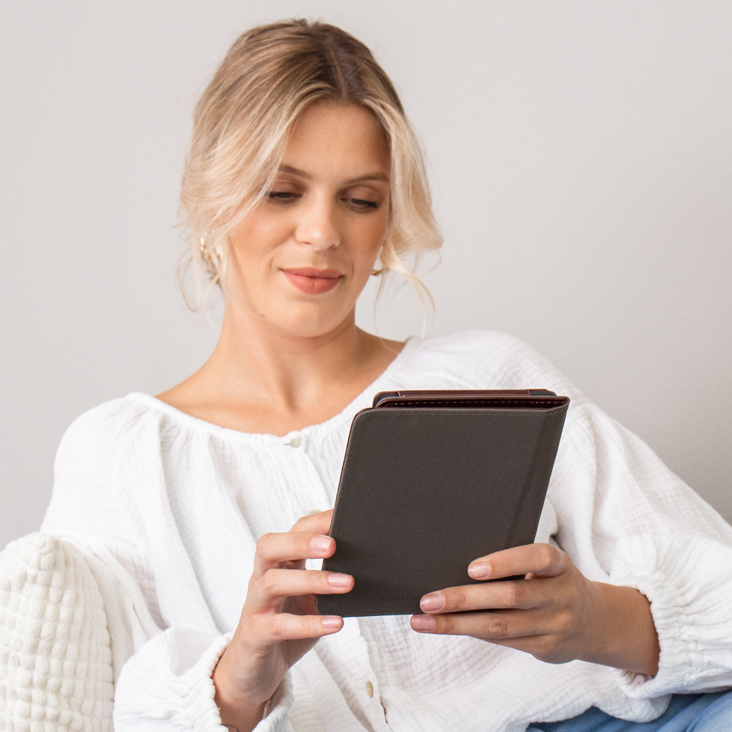 Woman looking at a tablet, with a light-colored top. Blonde hair.