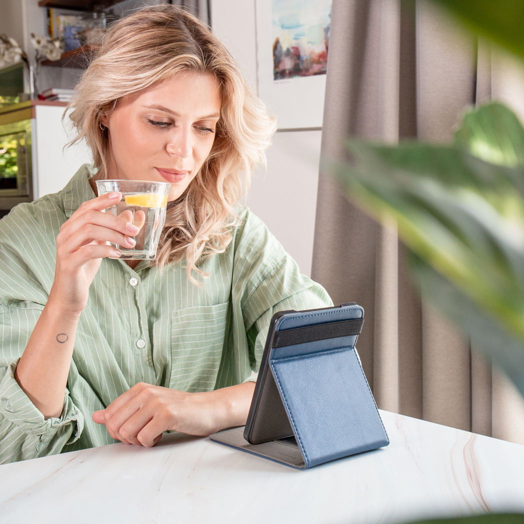 Een vrouw die een glas water vasthoudt en naar een telefoon kijkt.