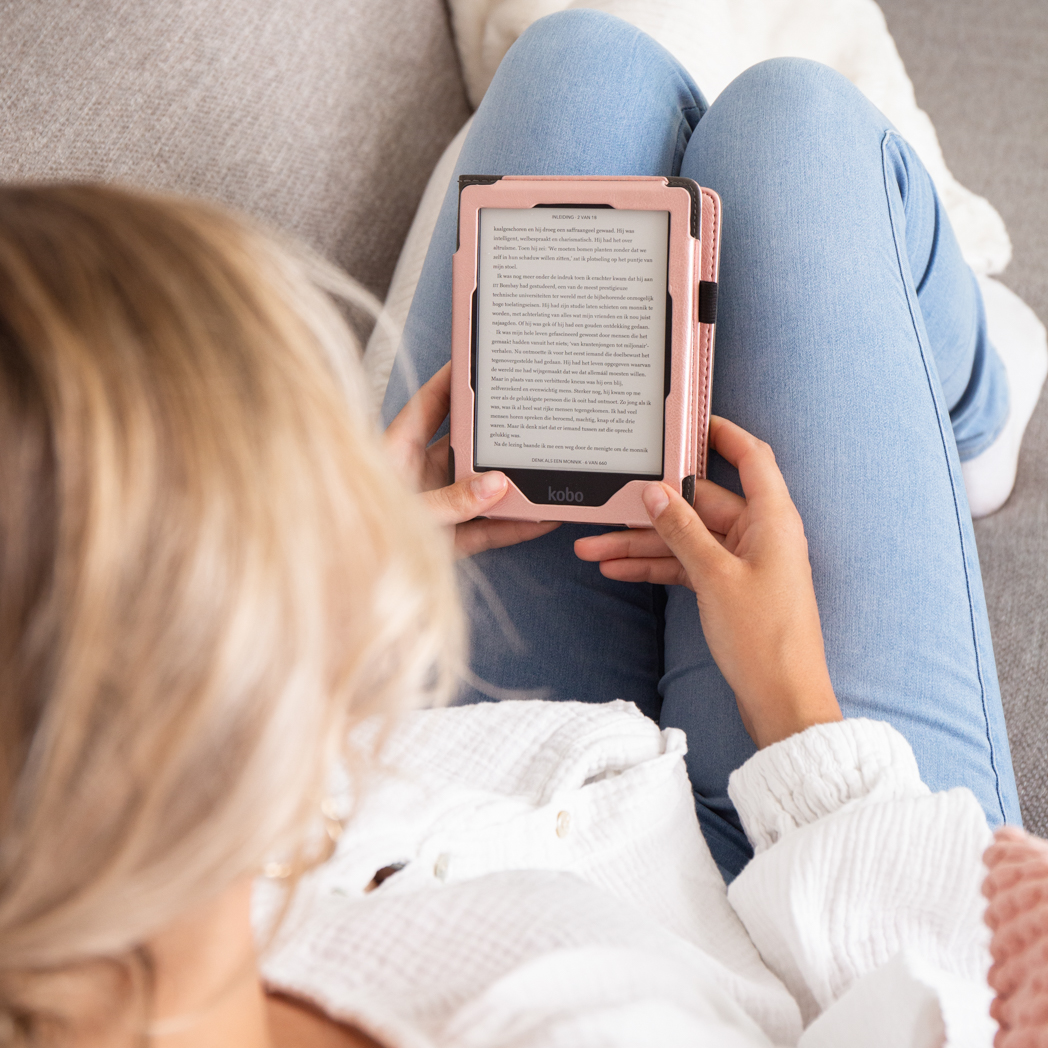 Person holding an e-reader with a pink case, reading, sitting on a sofa.