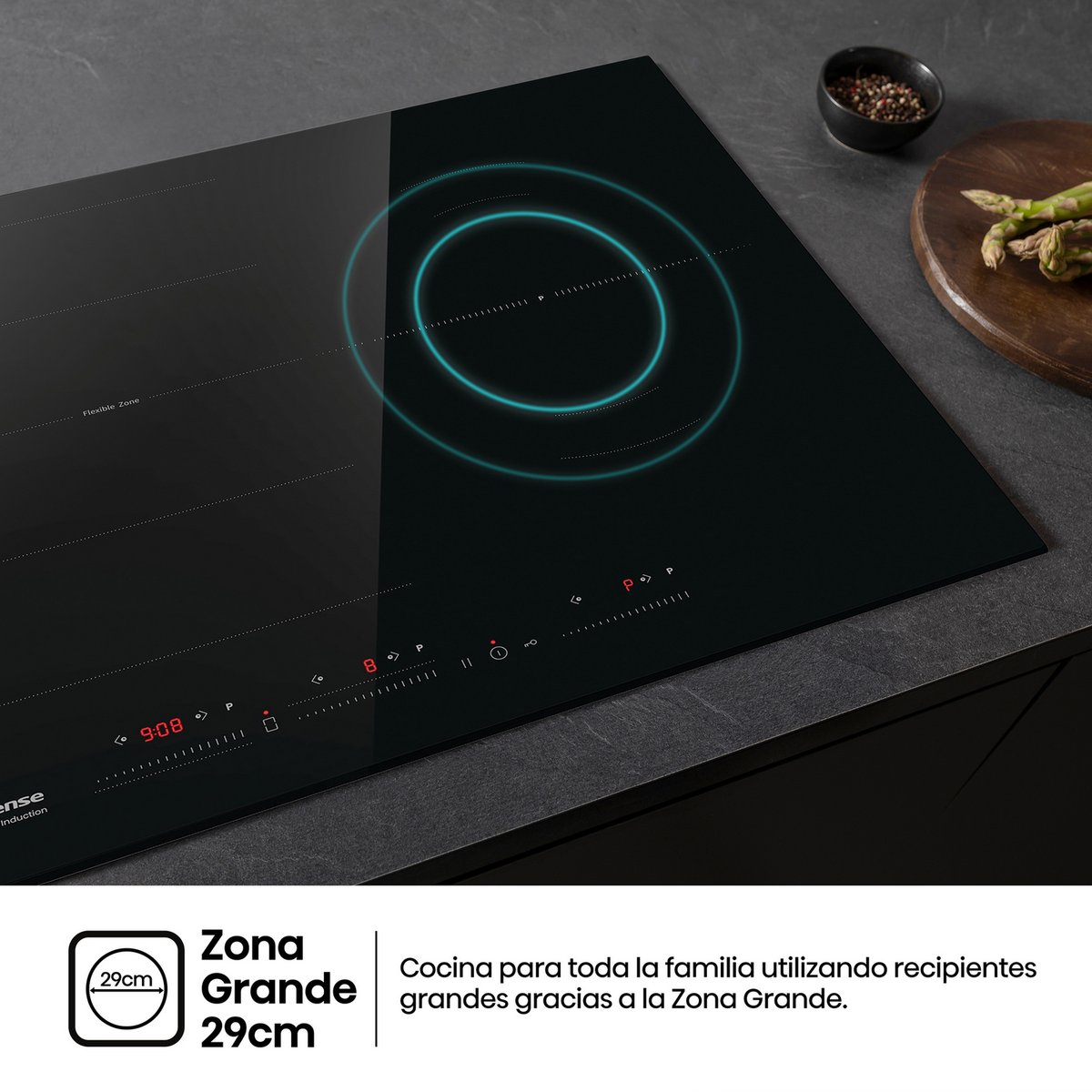 Czarna płyta indukcyjna. Okrągła strefa gotowania. Lekko rozmyte tło ze składnikami.