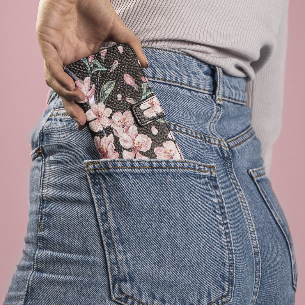 Main mettant une coque florale dans une poche de jean.