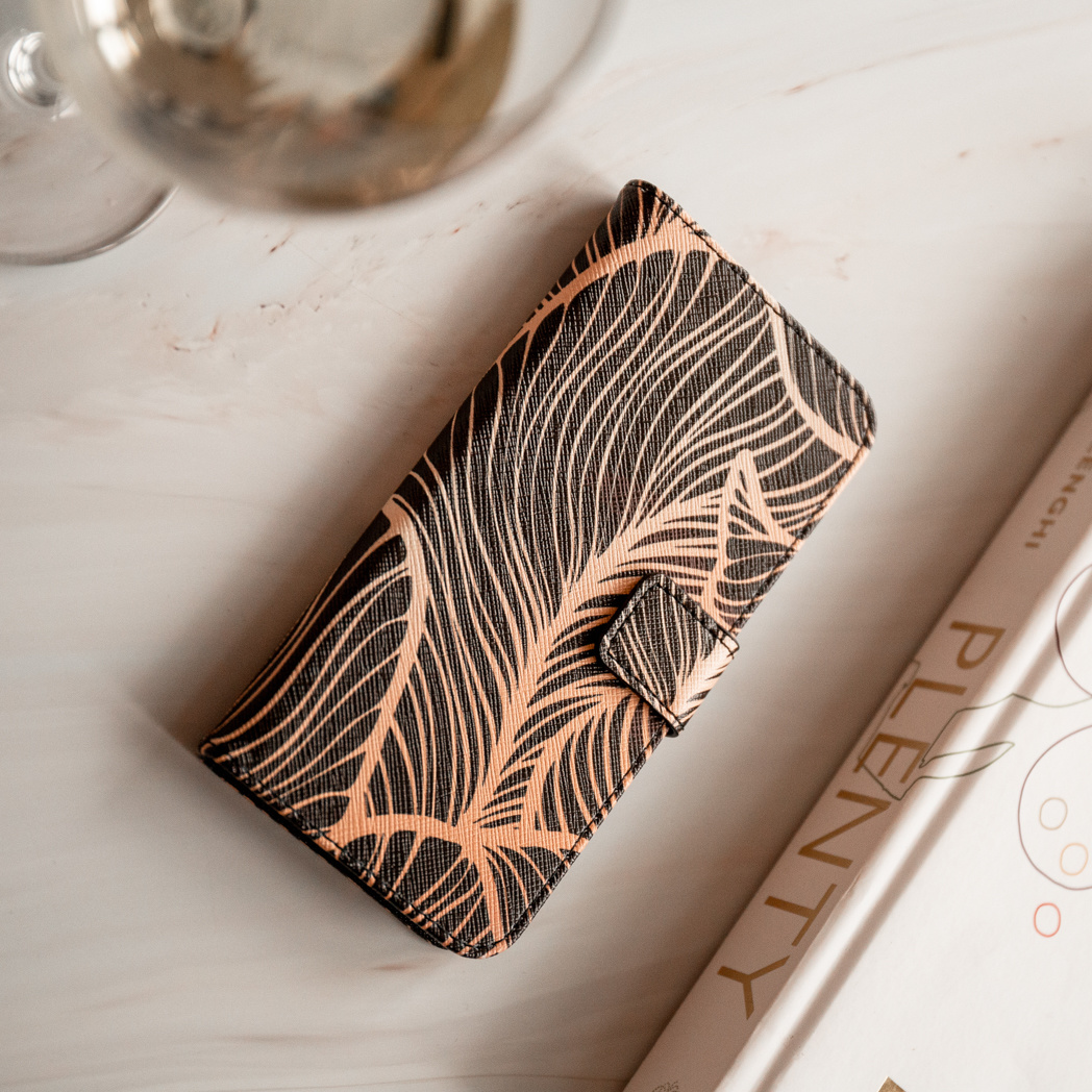 Een telefoonhoesje met een zwart en goud design, liggend op een wit oppervlak.