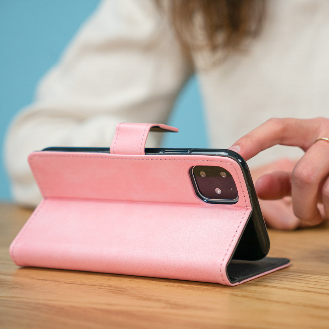 Un téléphone dans un étui rose est légèrement ouvert. Un doigt touche l'écran.