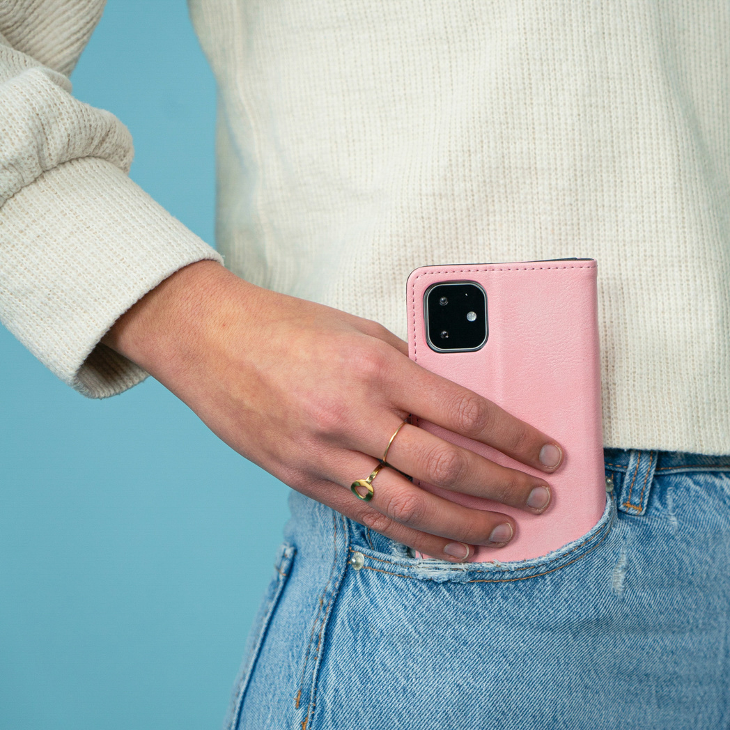 Personne en jean mettant un étui portefeuille rose dans une poche.