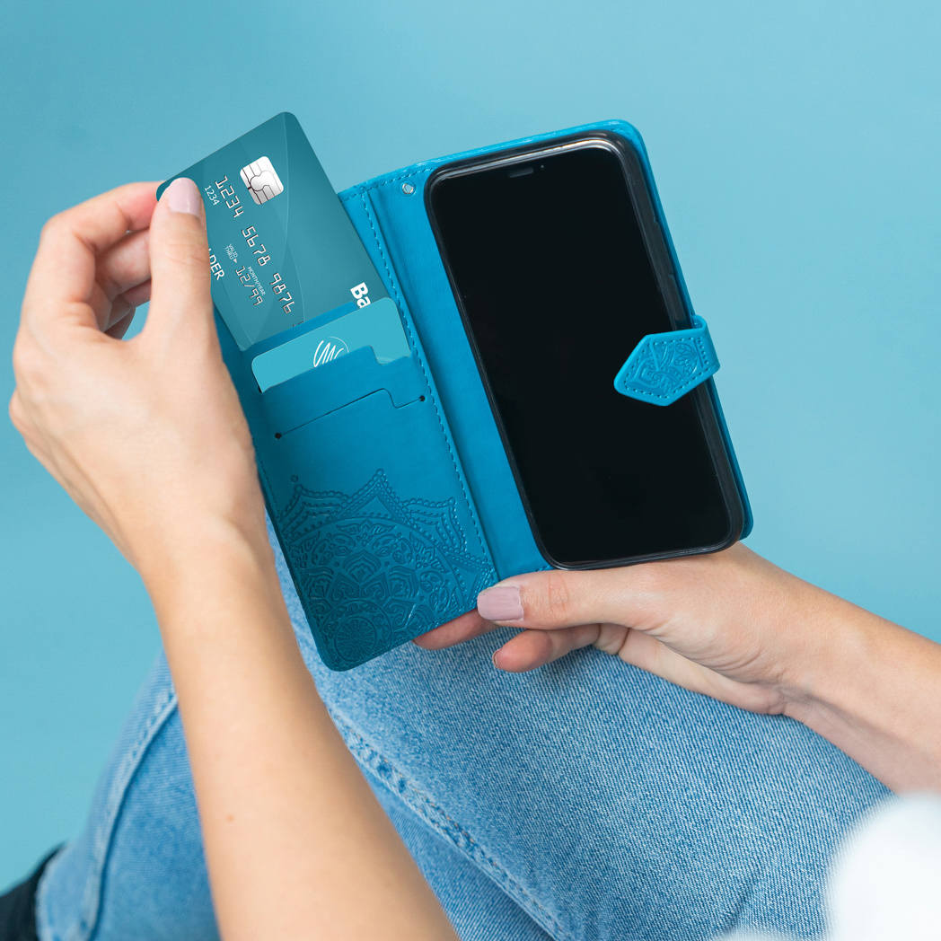 Persona che tiene una custodia blu per telefono, inserendo una carta di credito.