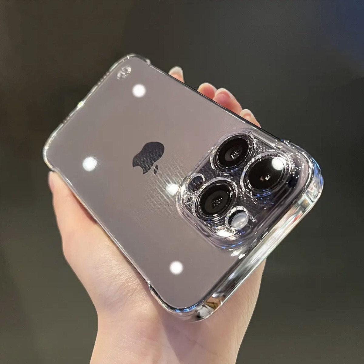 Mano che tiene un telefono con una custodia trasparente. Il telefono ha più obiettivi della fotocamera.