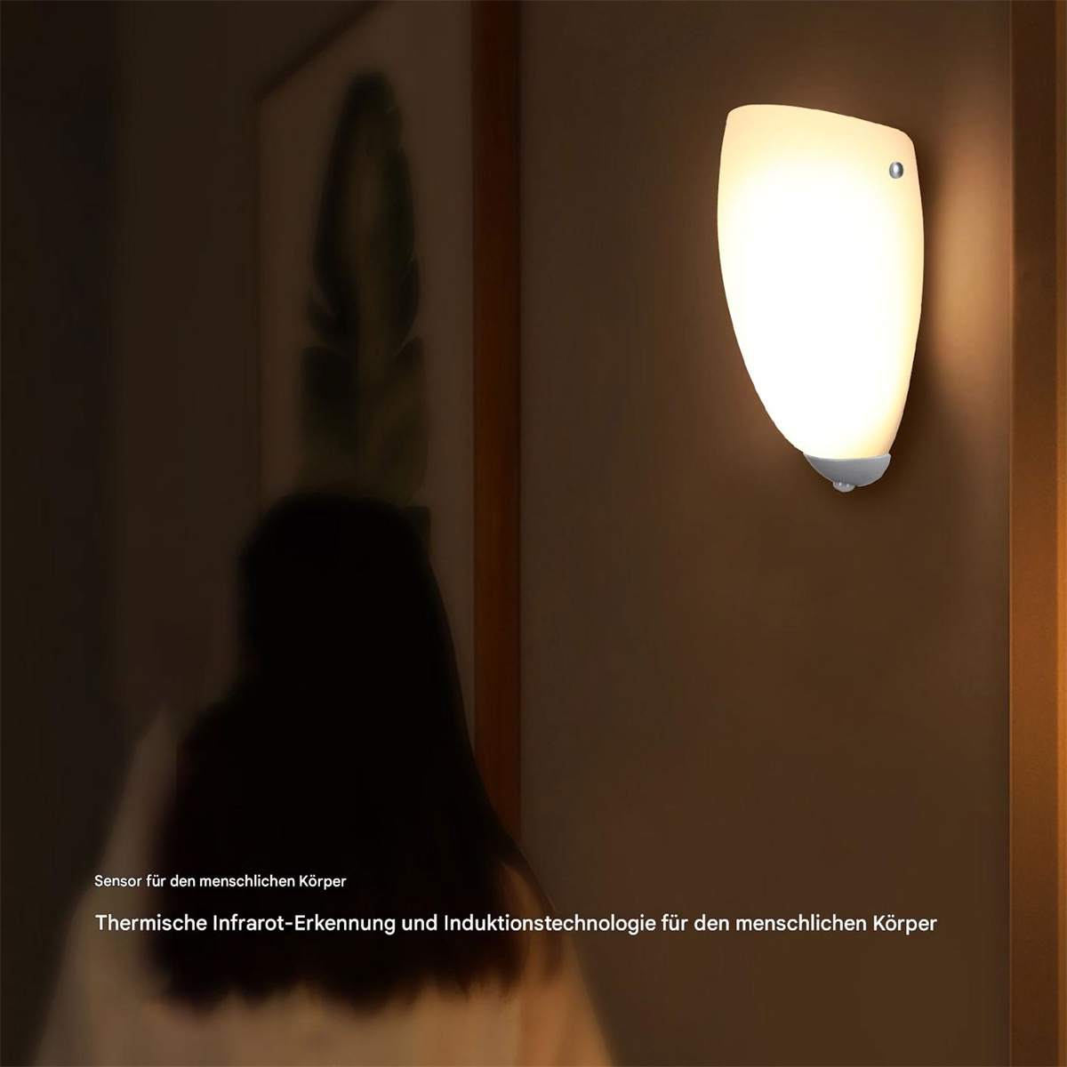 Wandlampe leuchtet, Person im Hintergrund unscharf. Licht weiß, mit Sensor unten. Dunkle Umgebung.