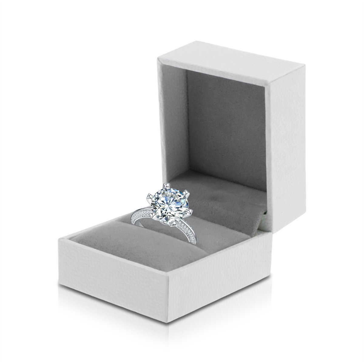 Ein Diamantring in einer offenen weißen Schachtel mit grauem Samtinnenraum auf weißem Hintergrund.
