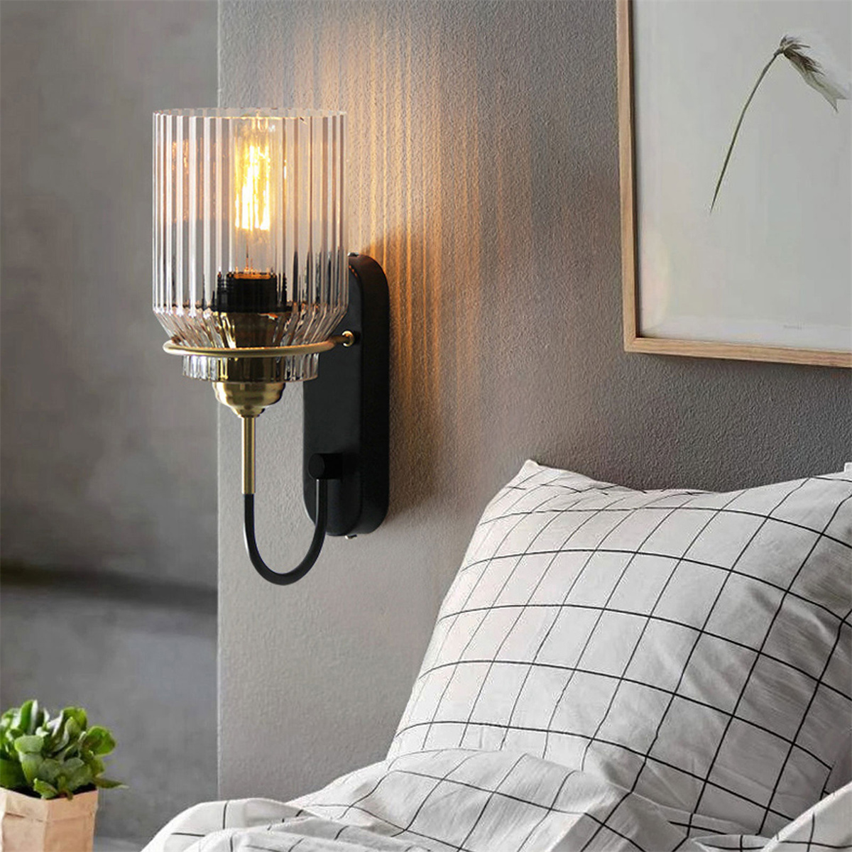 Wandlampe mit Glasschirm und Metallarm, an einer Wand montiert.