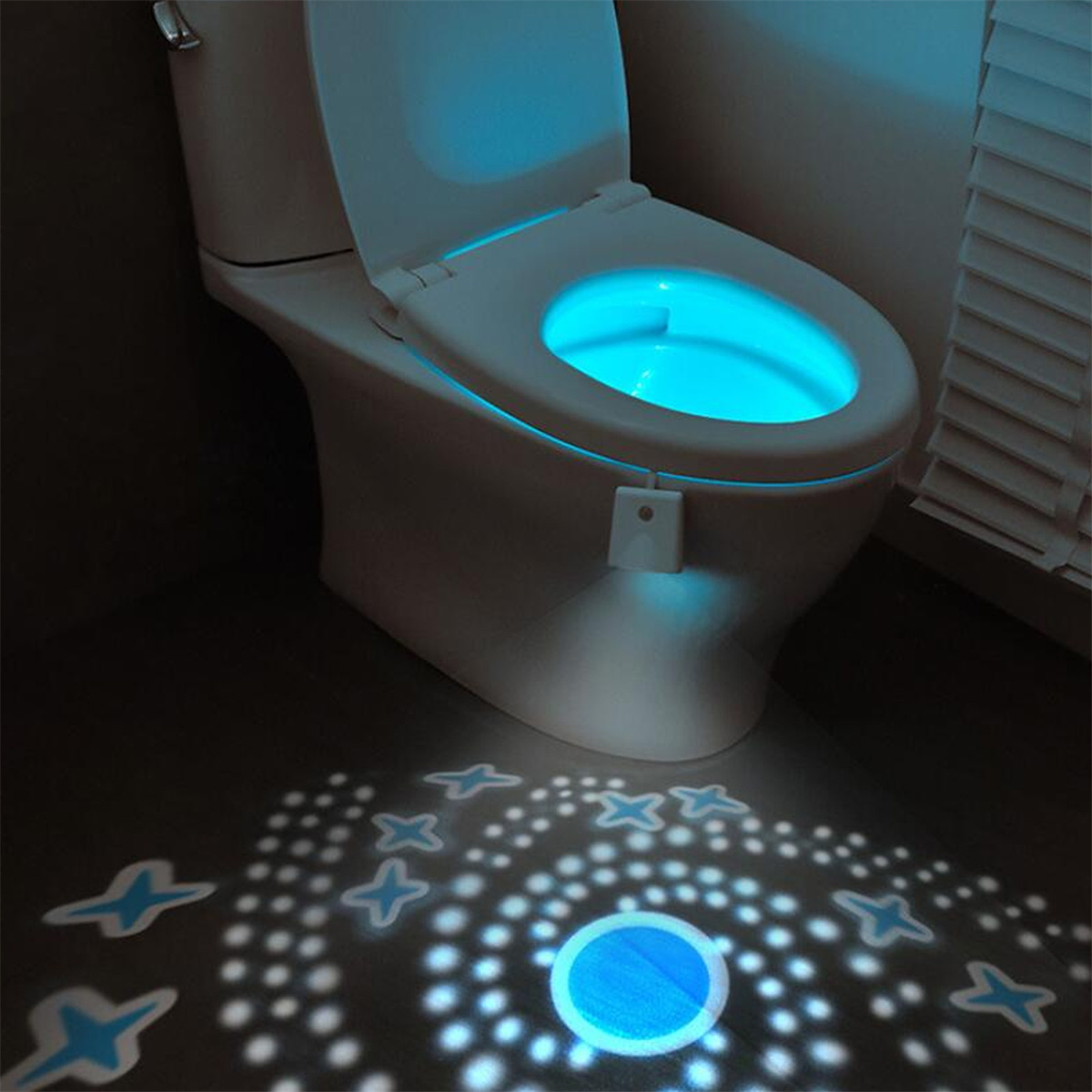 Toilette mit blauem Licht, das aus der Schüssel kommt. Sterne werden auf den Boden projiziert.